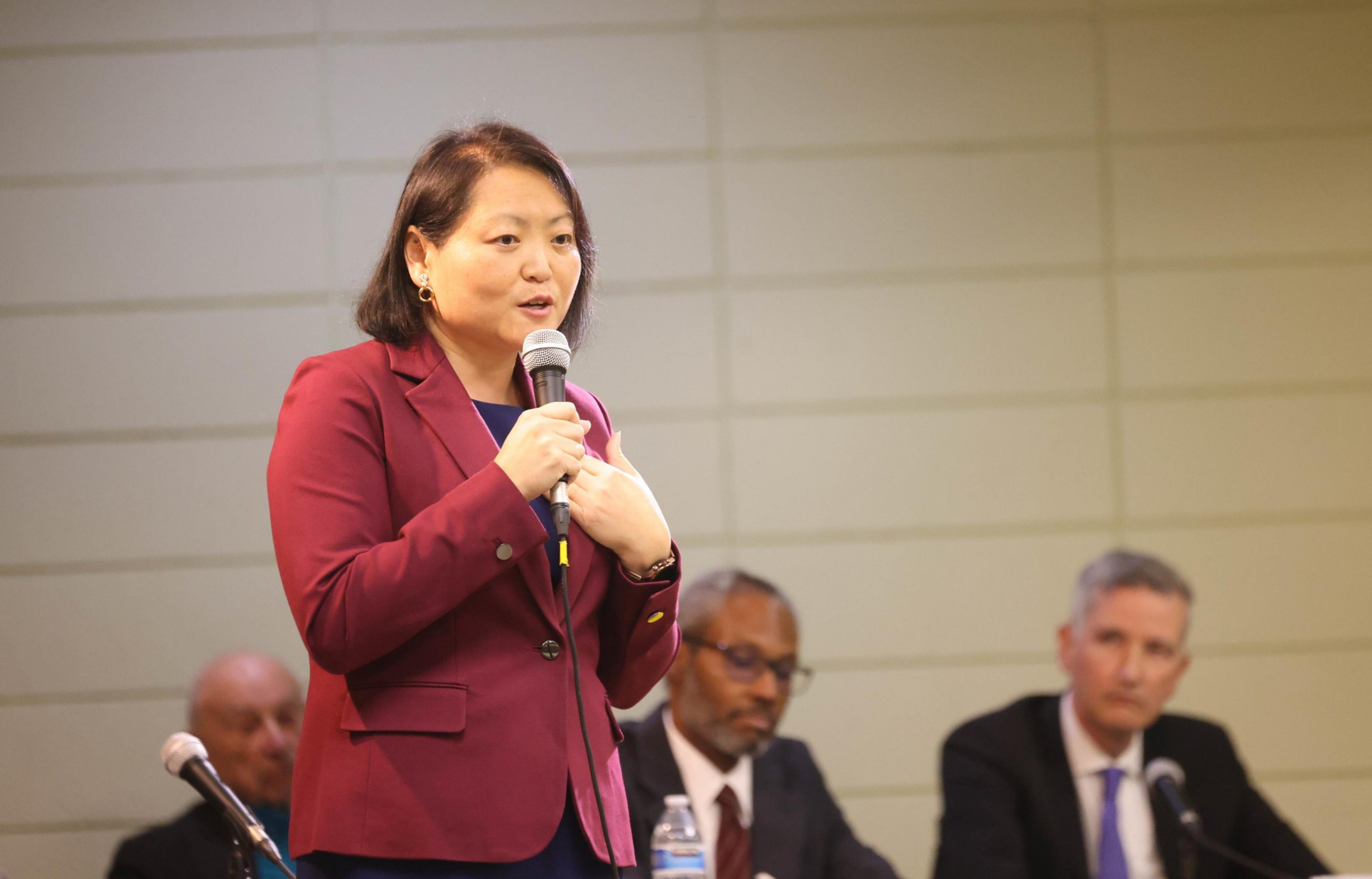 A woman stands on a stage with a microphone in her hand.