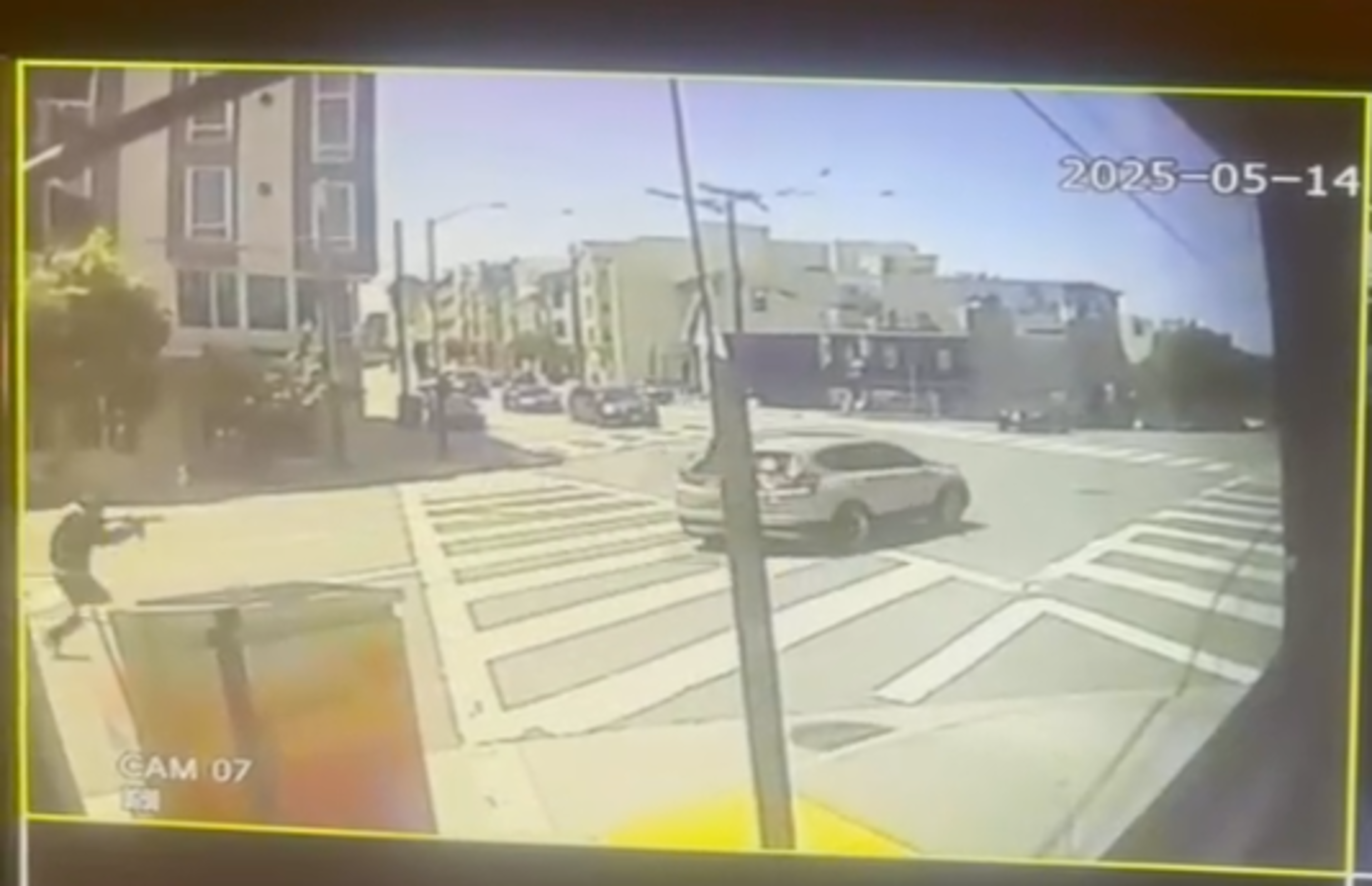 A city intersection with crosswalks is shown on a sunny day. Cars are visible on the street, and a pedestrian stands on the sidewalk. The date reads 2025-05-14.