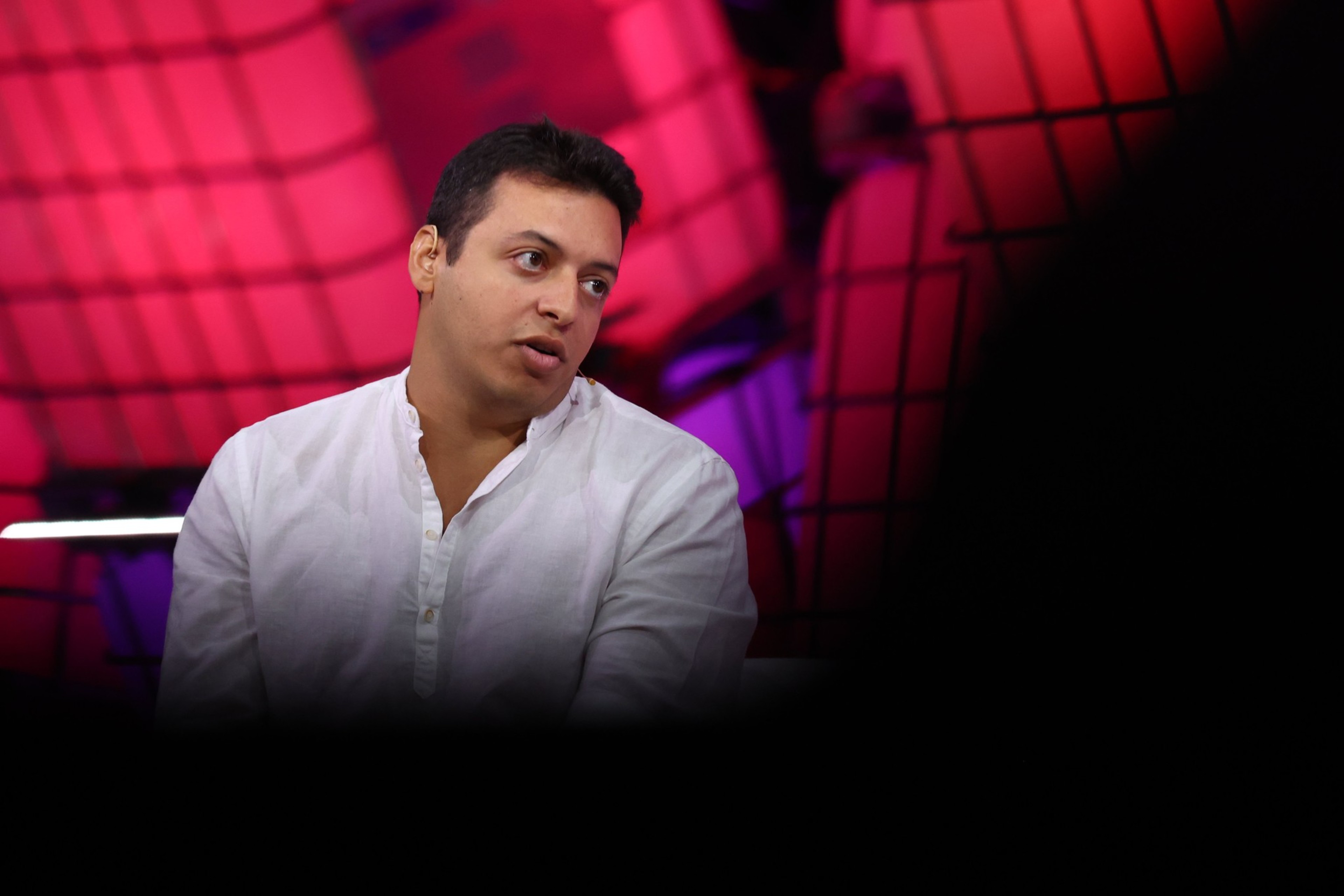 A person in a white shirt is partially visible, surrounded by a blurred, red and black grid-like background with a large dark area obscuring the bottom.