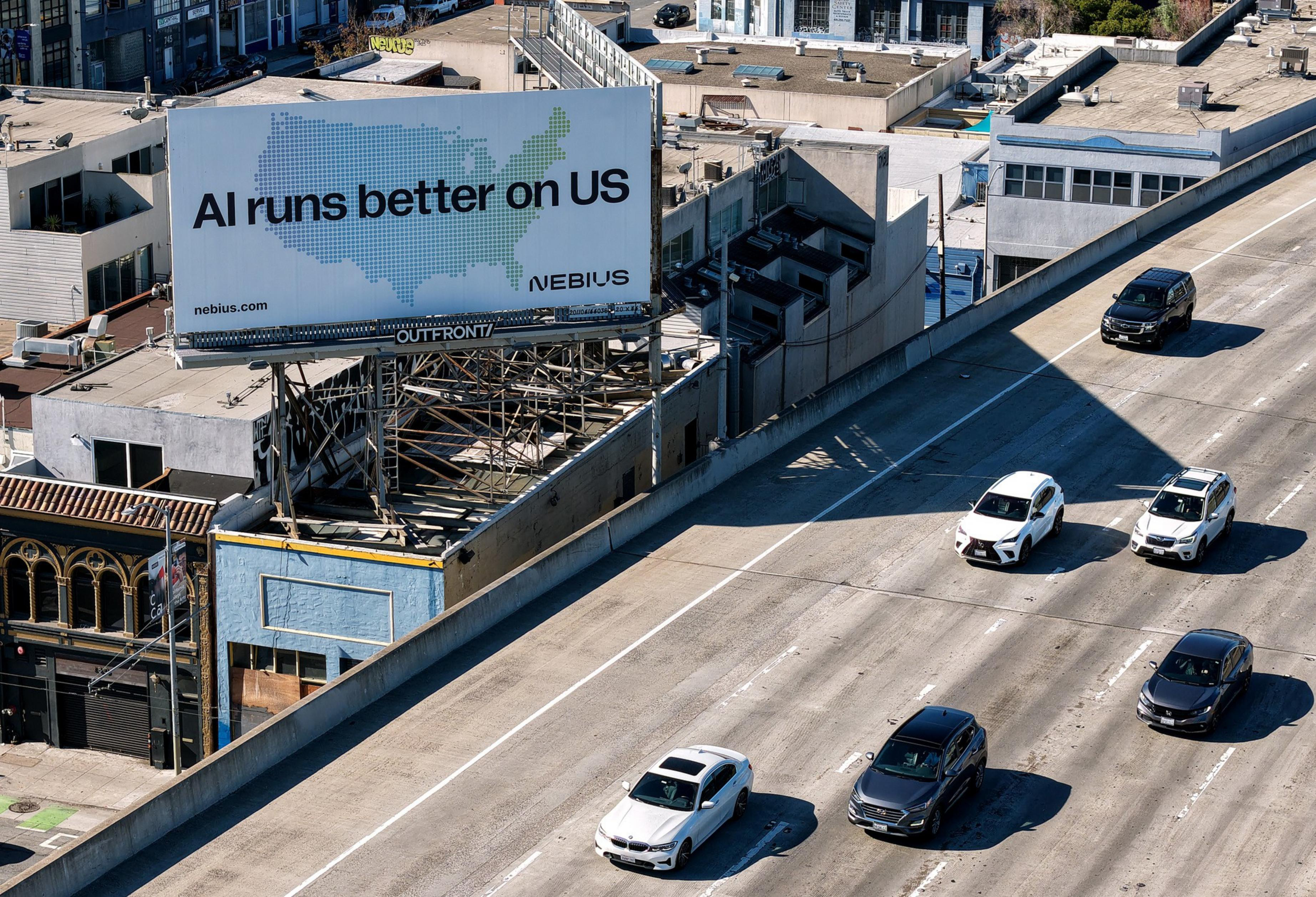 A billboard above a city highway reads "AI runs better on US" with a map of the United States, while several cars drive along the road below.