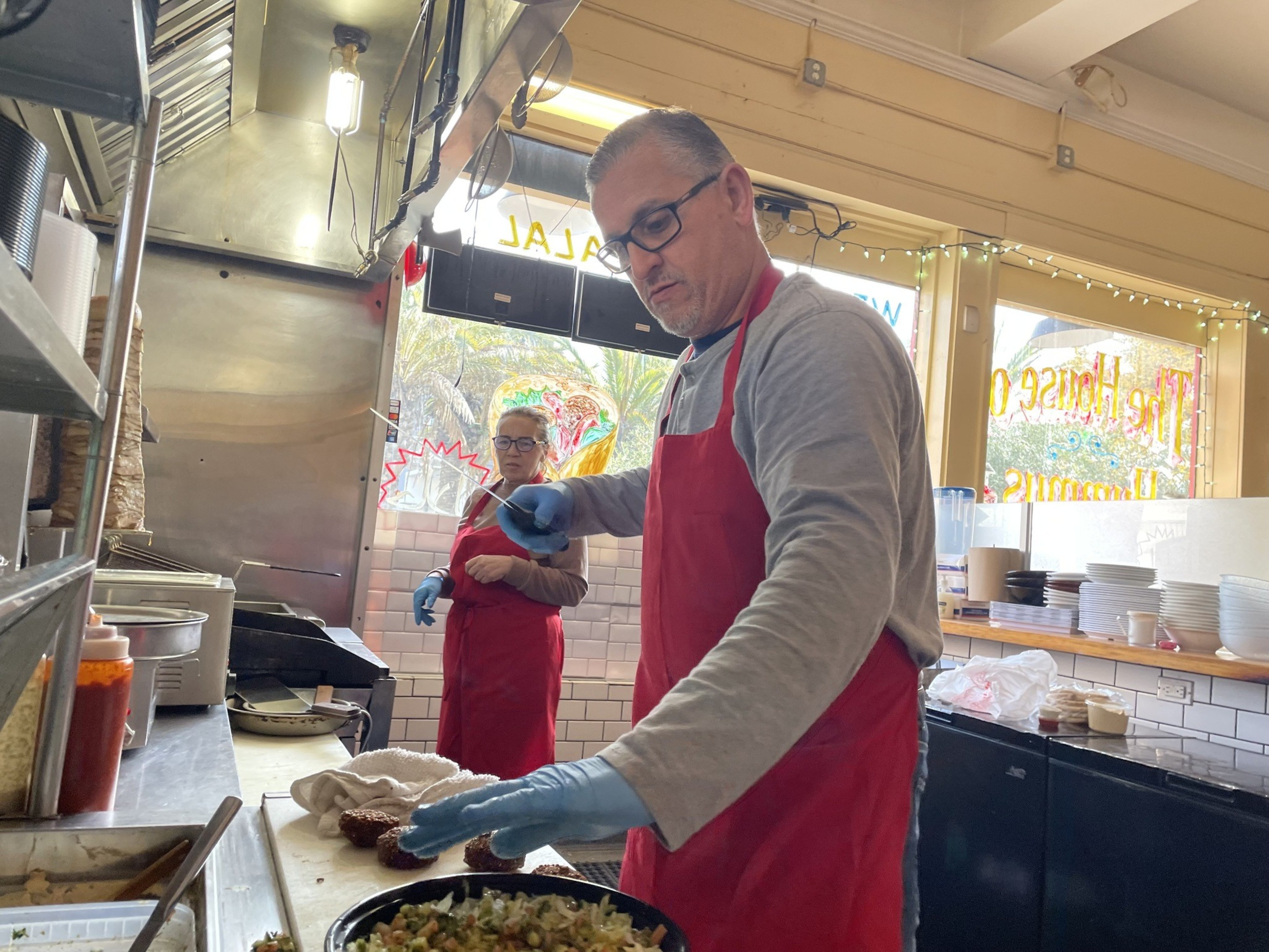 A man wearing an apron prepares food with a knife.