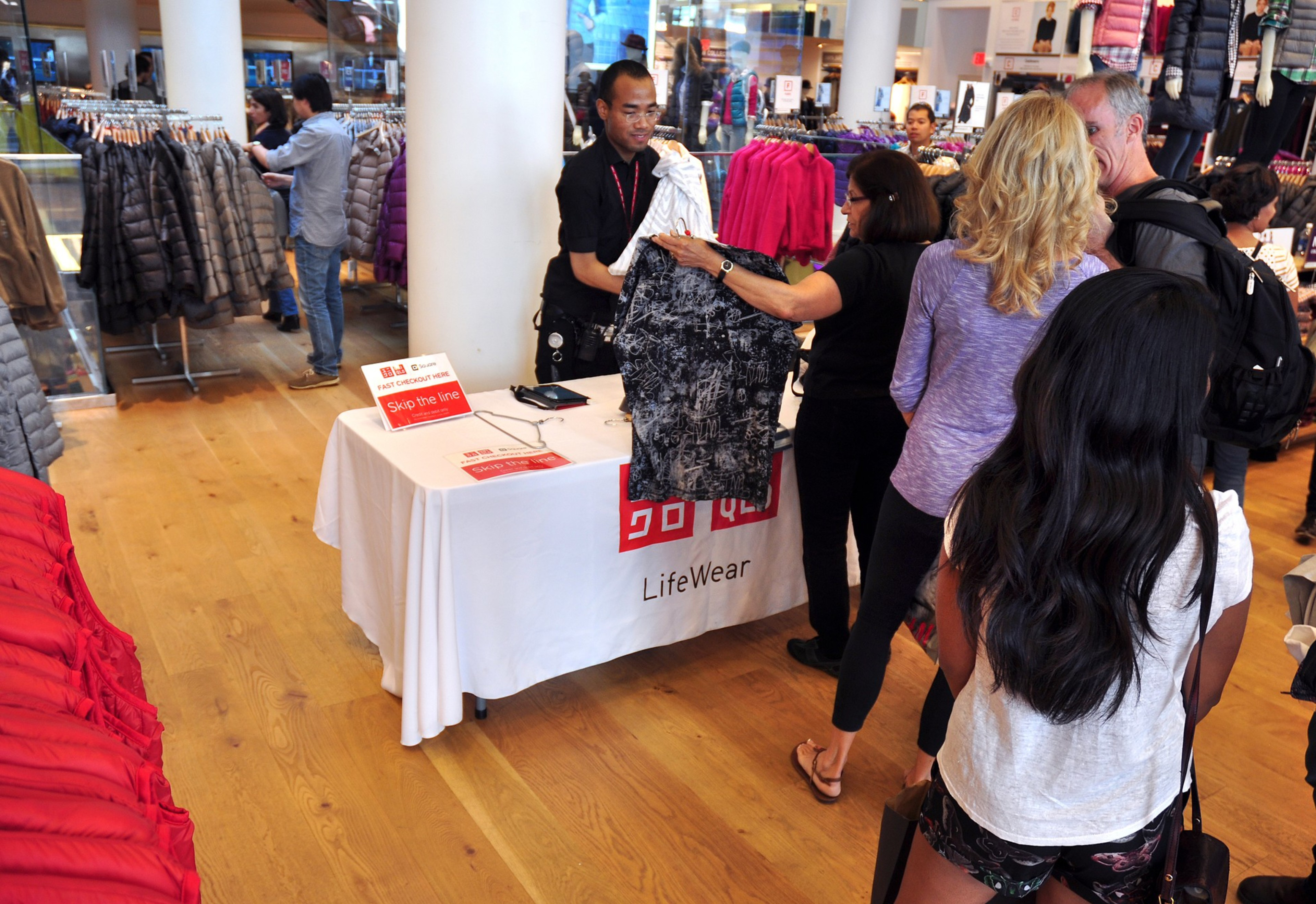 shoppers wait in line with clothes