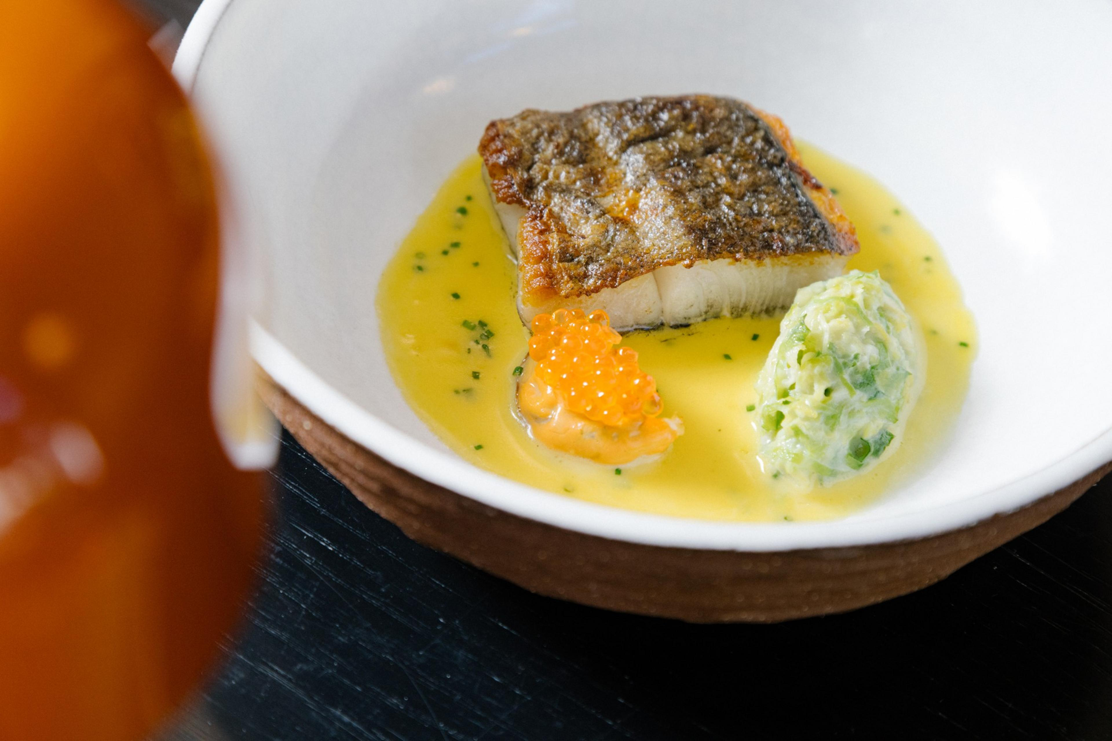 Seared black cod, confit sunchoke, fermented aioli, and shellfish broth await guests at 7 Adams.