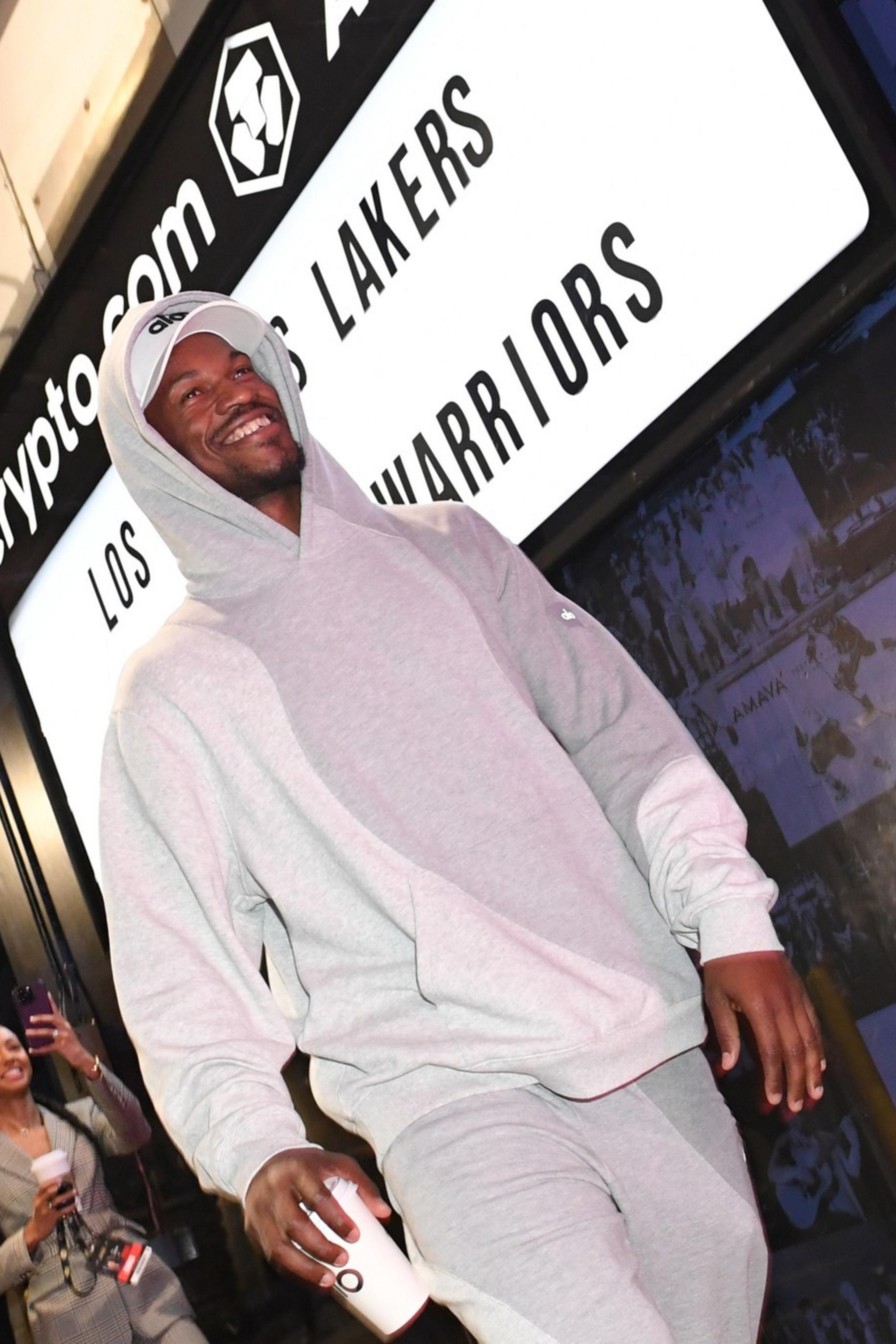 A man wearing sweatpants walking with a cup.