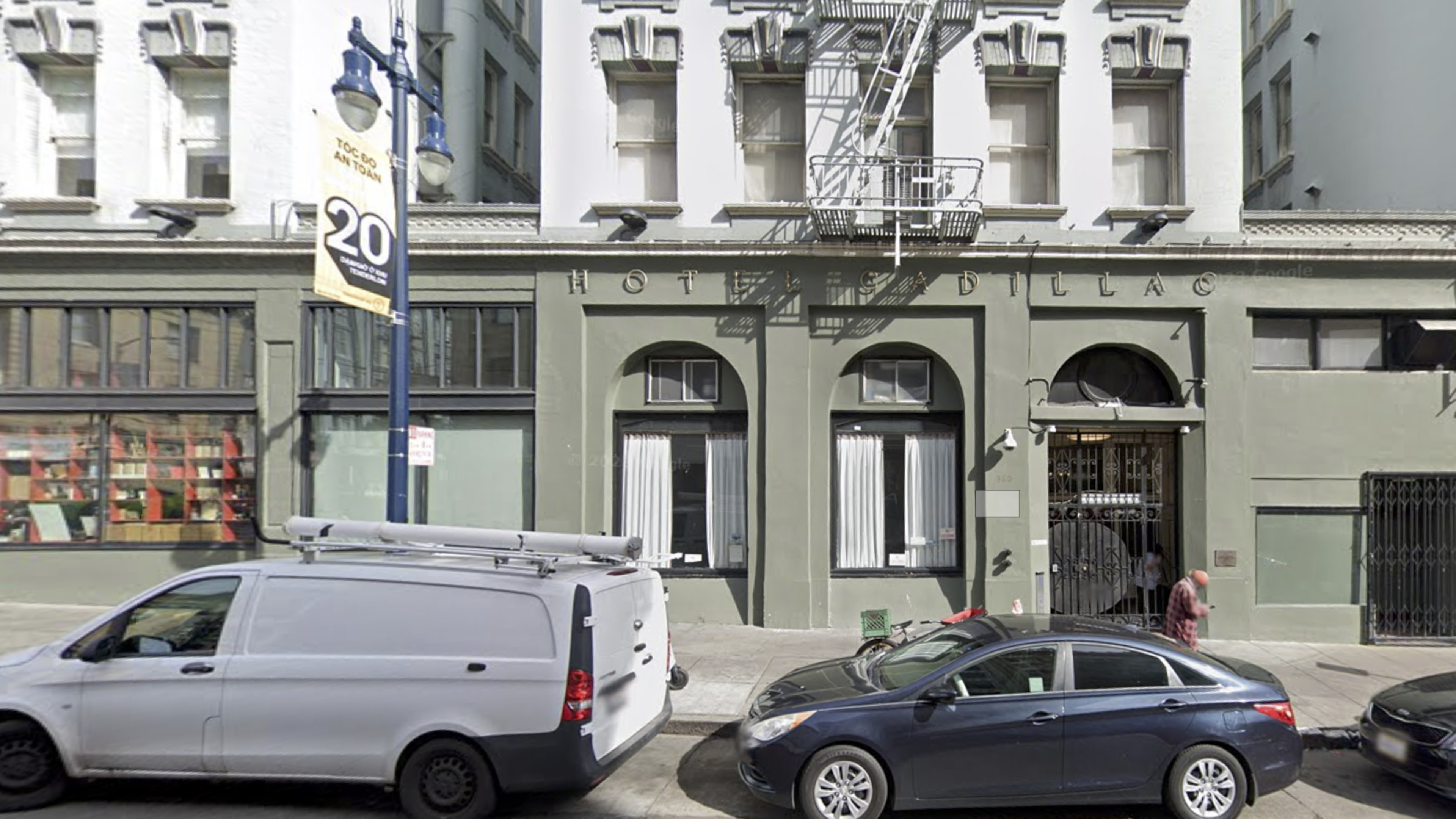 An exterior of a green and white apartment building with a fire escape and a sign reading "Hotel Cadillac"