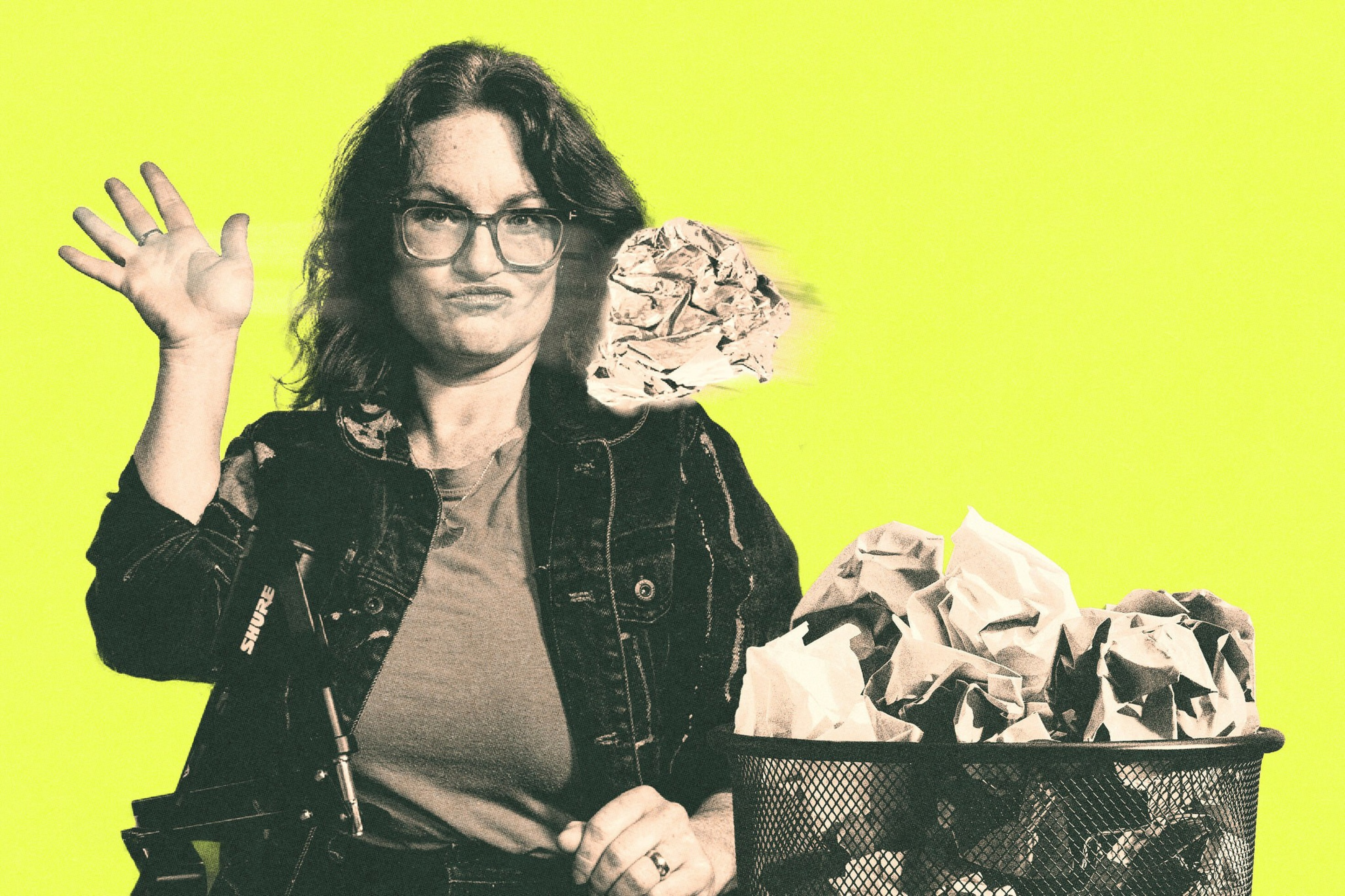 A woman with glasses and a denim jacket throws a crumpled paper ball into a full metal trash bin against a bright yellow background.
