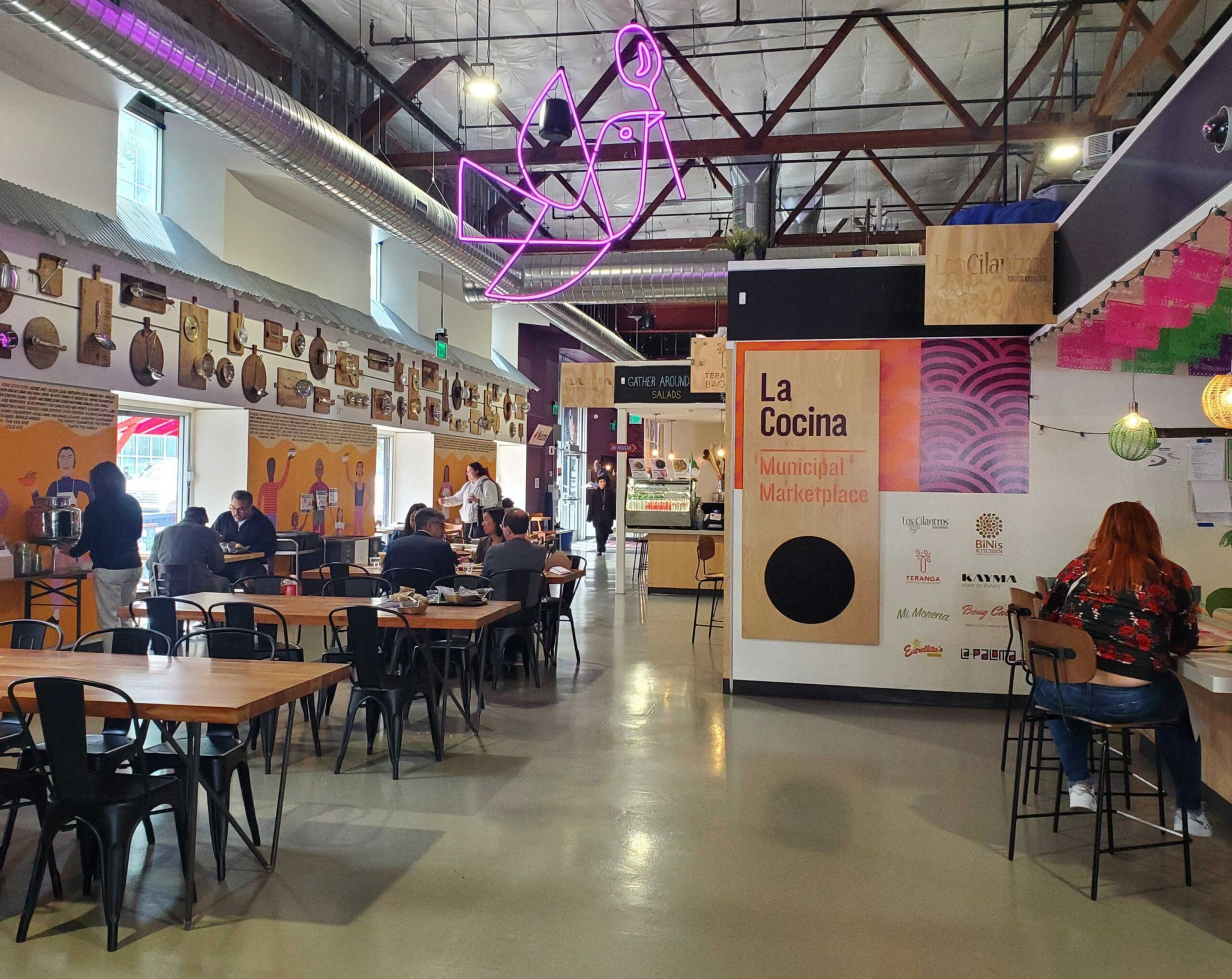 a large dining hall with high ceilings, several kiosks and a few patrons
