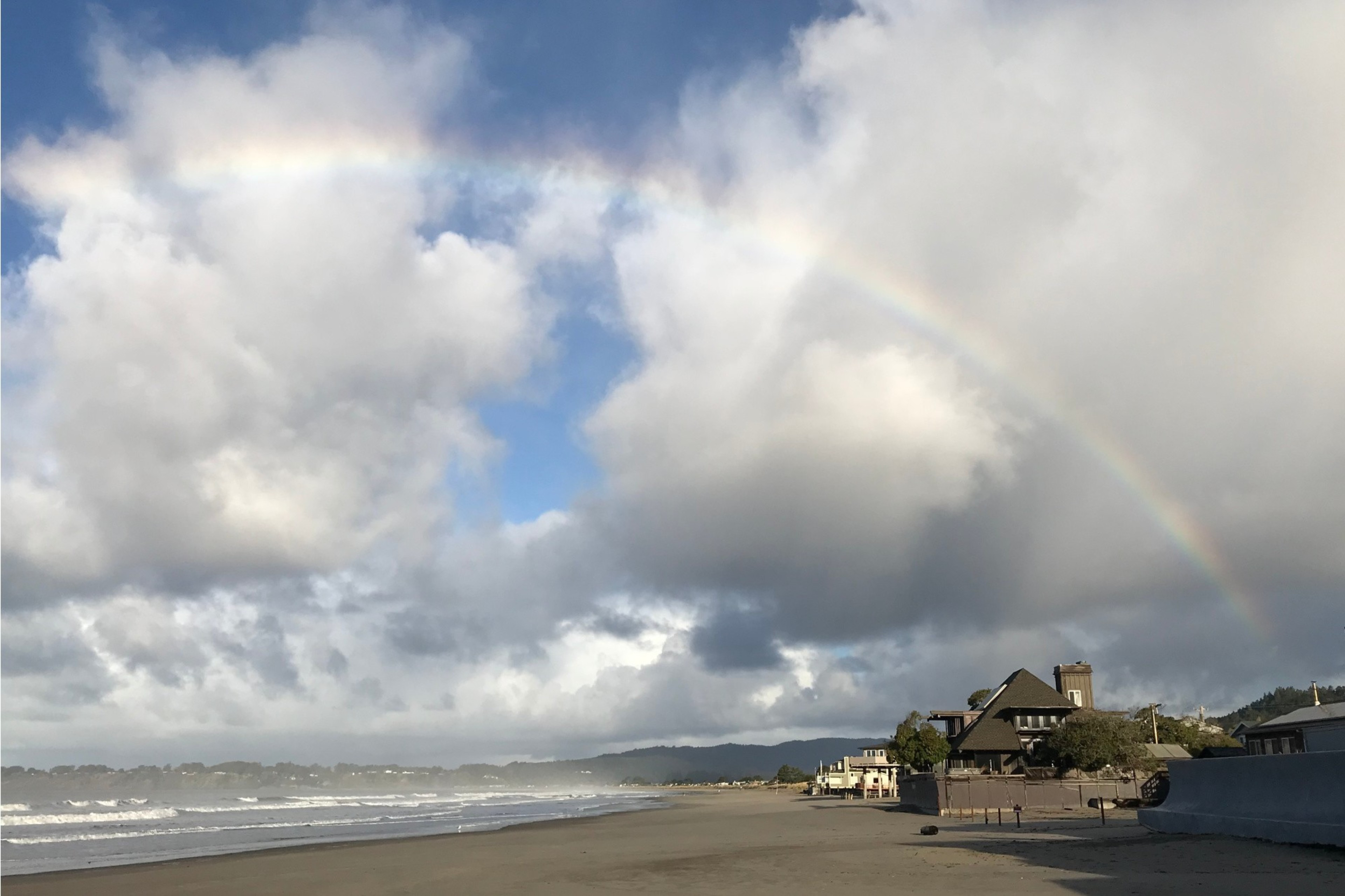 A cloudy day at the beach with a hint of a rainbow.