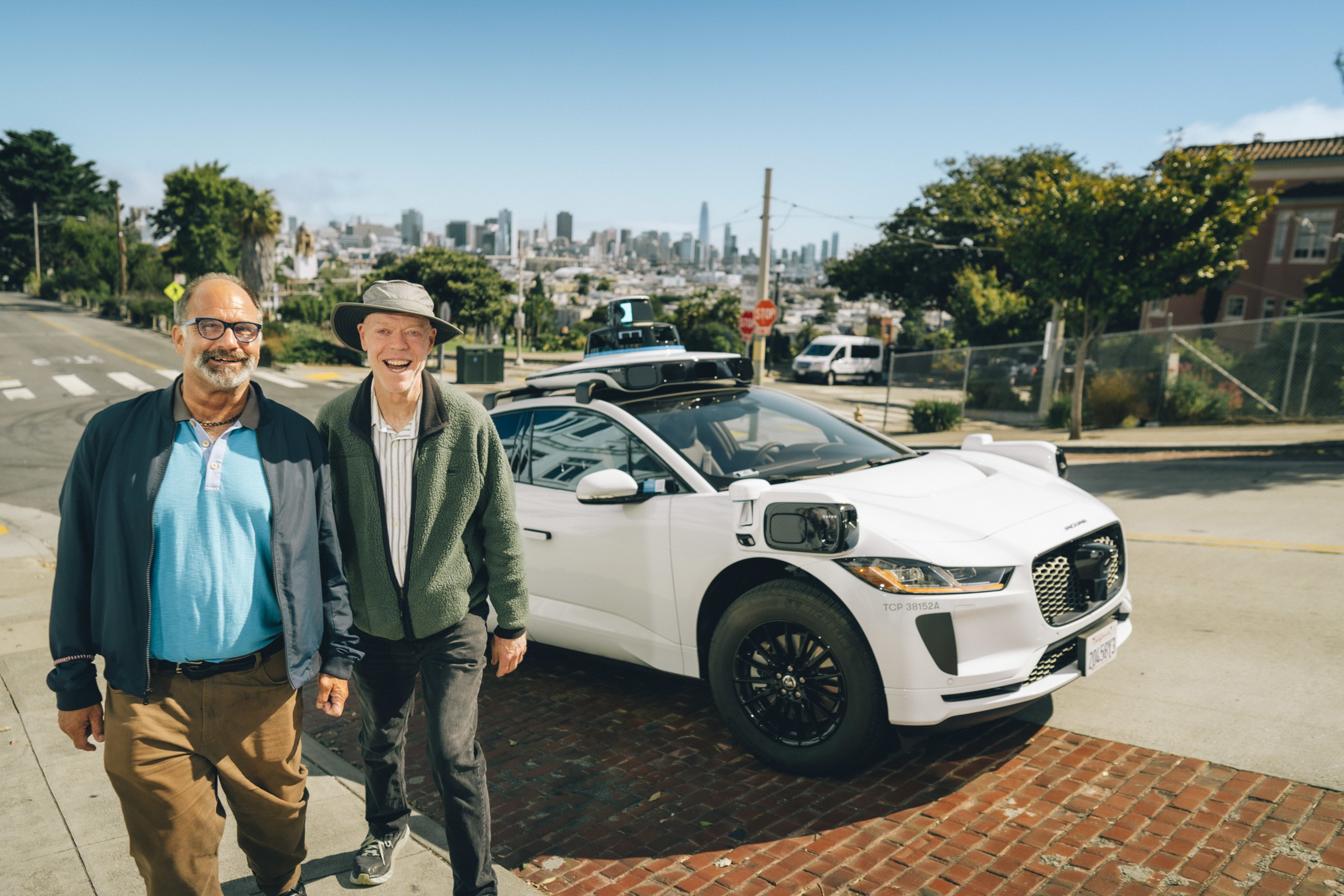 Steve and Newton pose in front of a Waymo during their Joy Ride in San Francisco.
