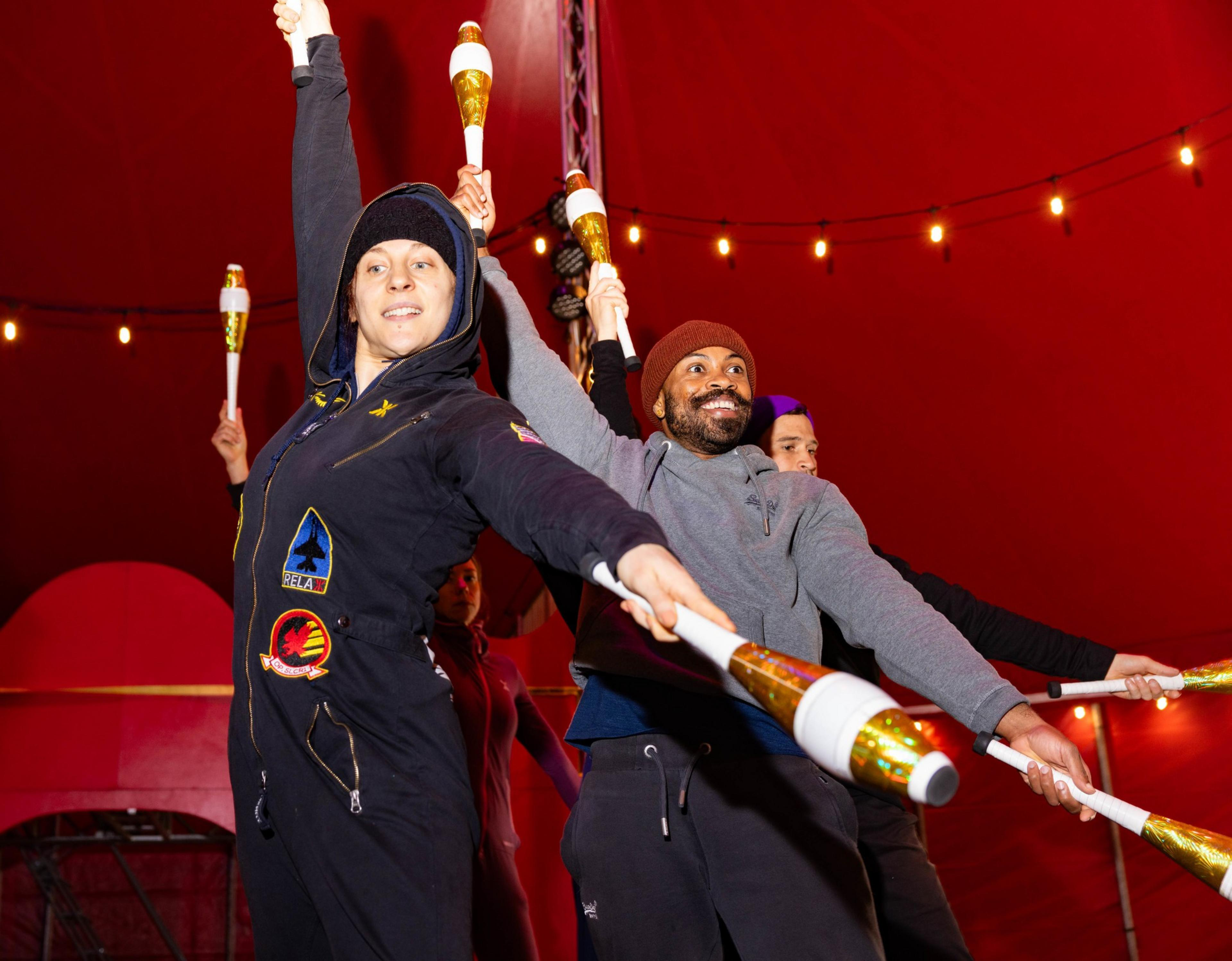 A group of people practice inside the a red circus tent.
