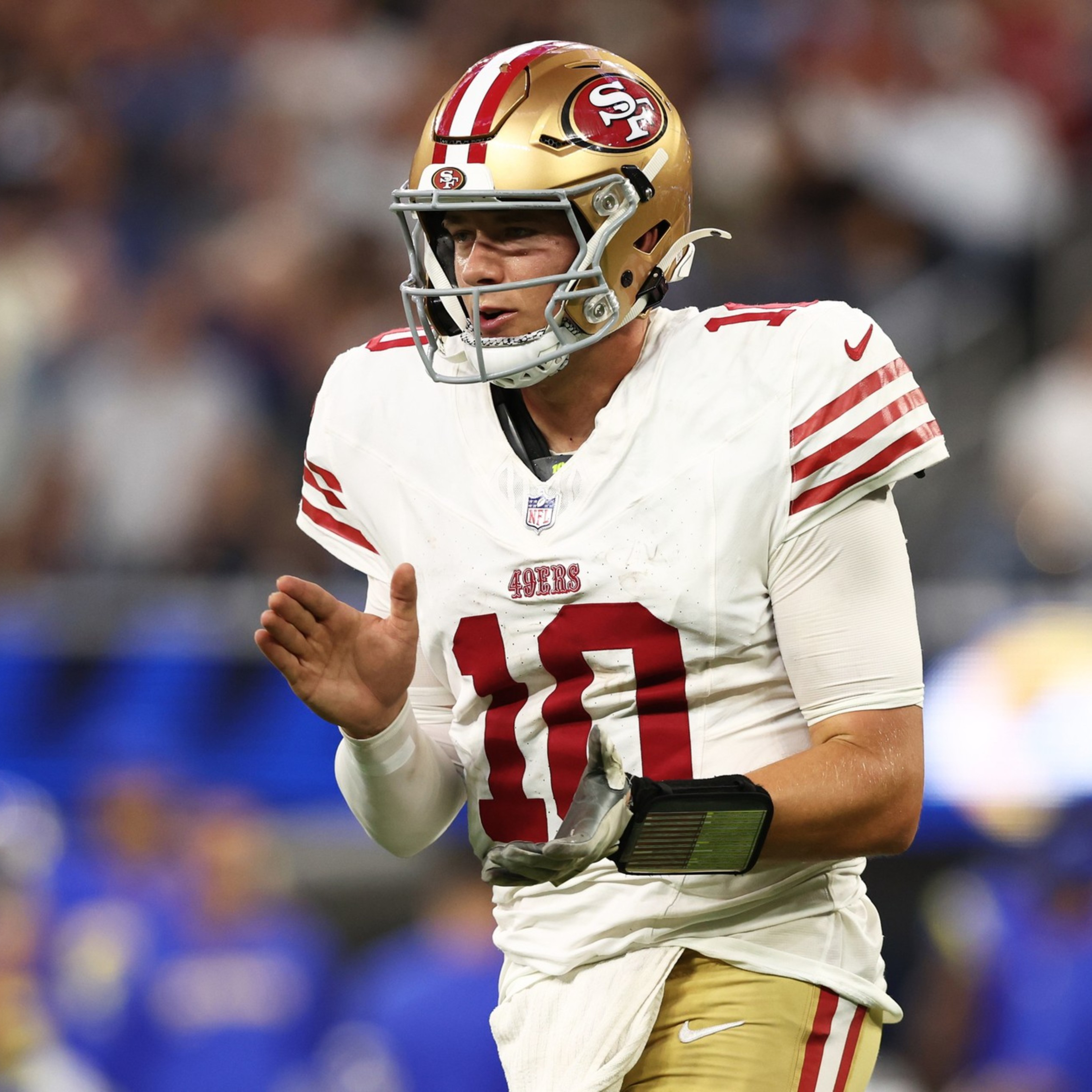 A San Francisco 49ers football player, wearing number 10, is clapping his hands on the field during a game.