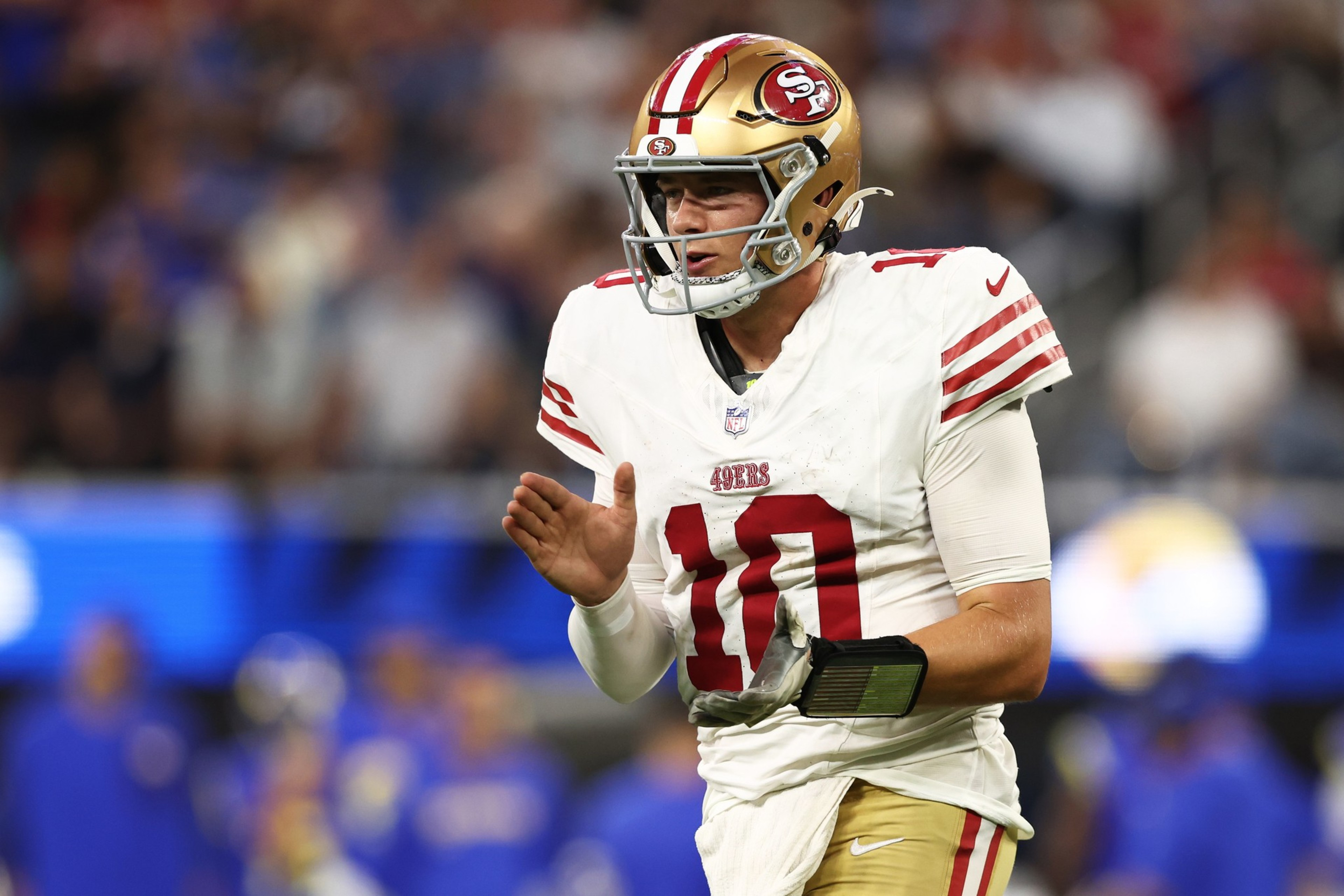 A San Francisco 49ers football player, wearing number 10, is clapping his hands on the field during a game.