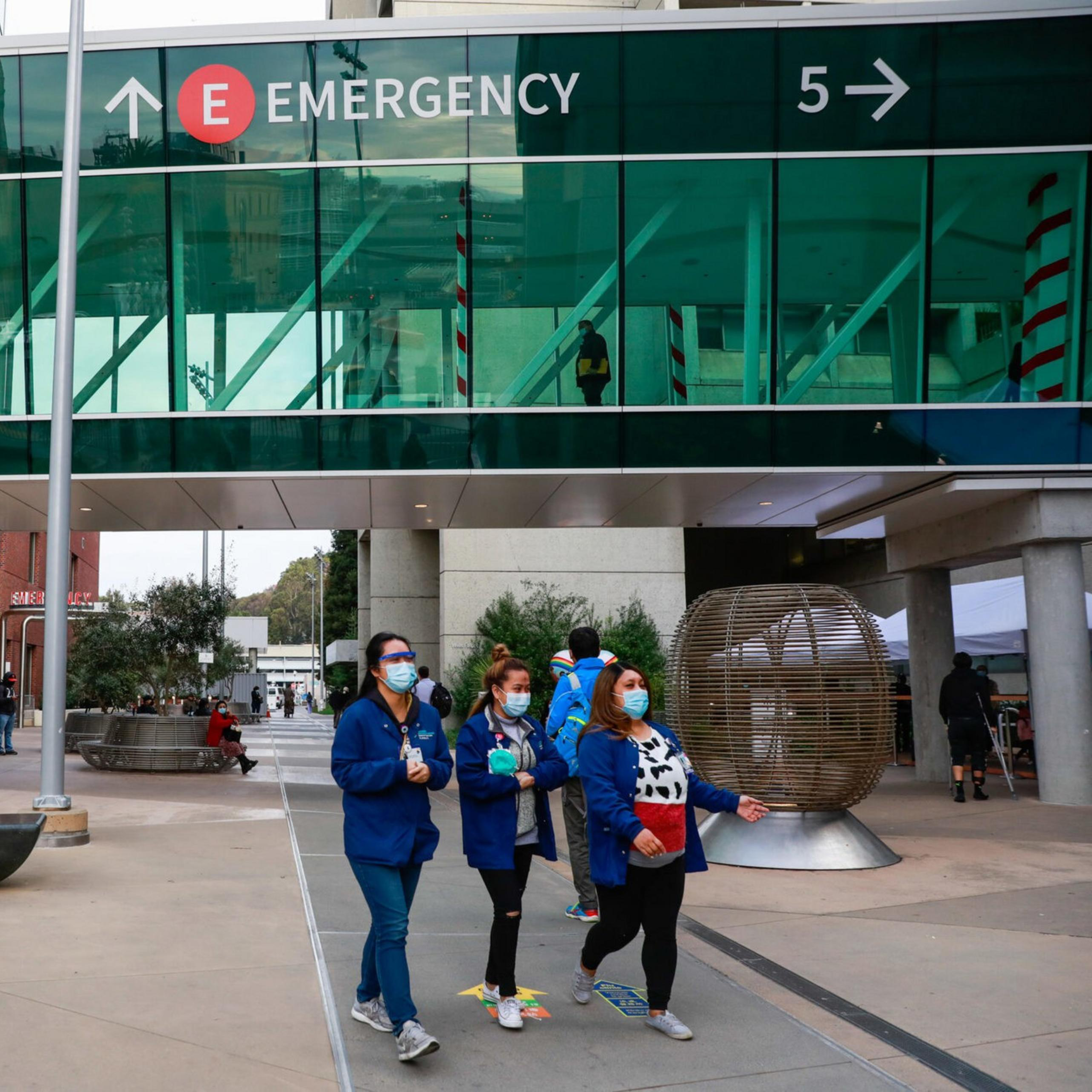 people walk outside emergency sign at hospital