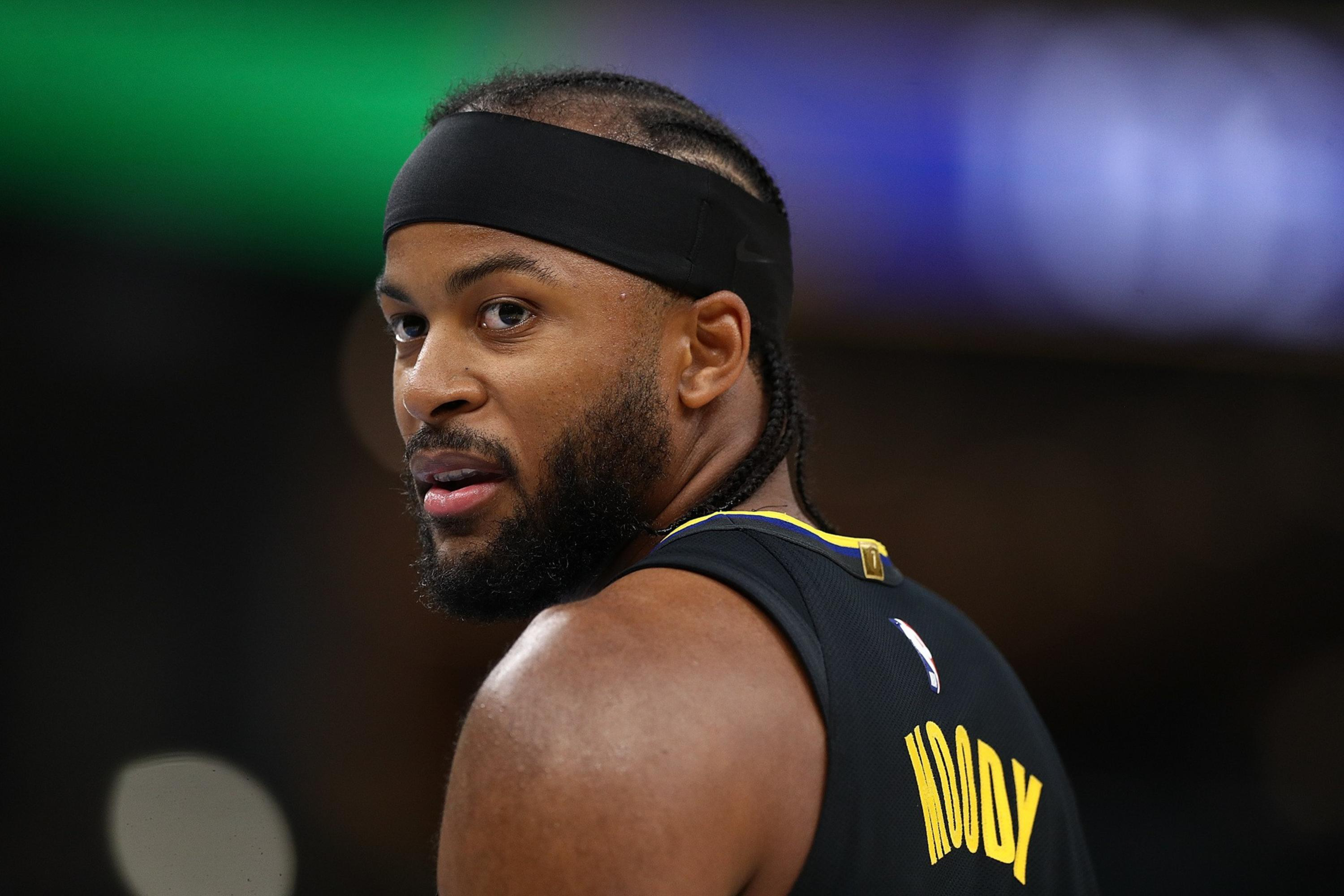 A basketball player wearing a black headband and jersey with the name “Moody” looks over his shoulder with a focused expression.
