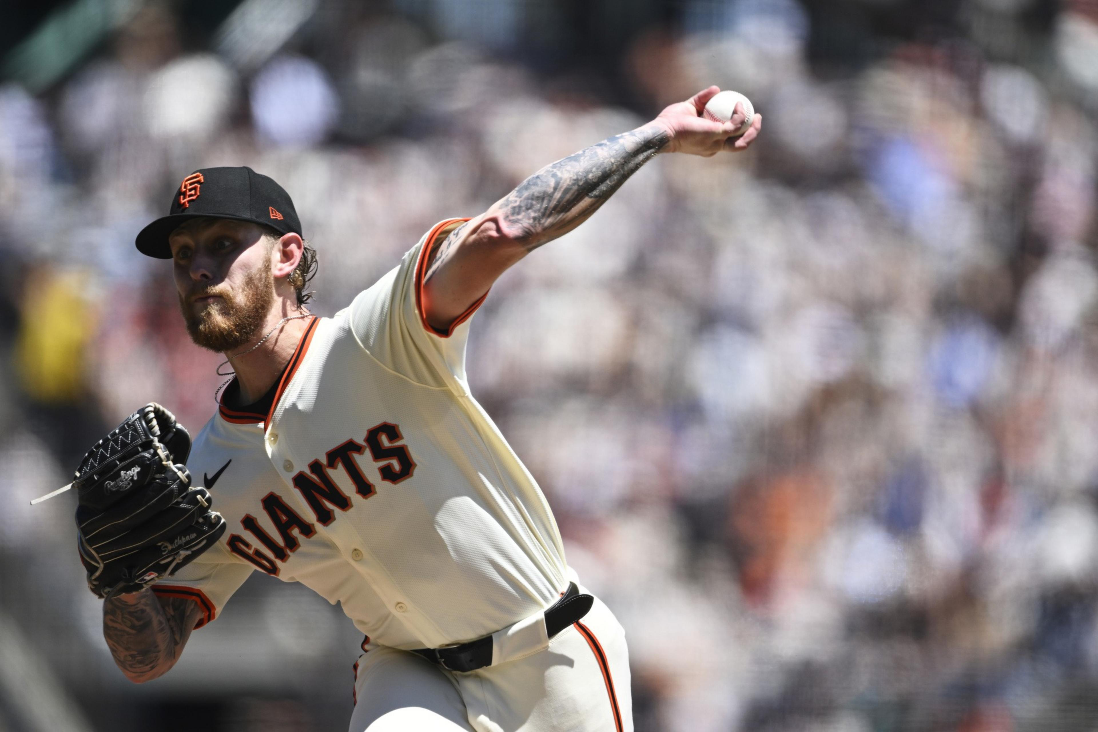 A baseball pitcher wearing a San Francisco Giants uniform throws a pitch with intense focus, his right arm extended forward and glove raised.
