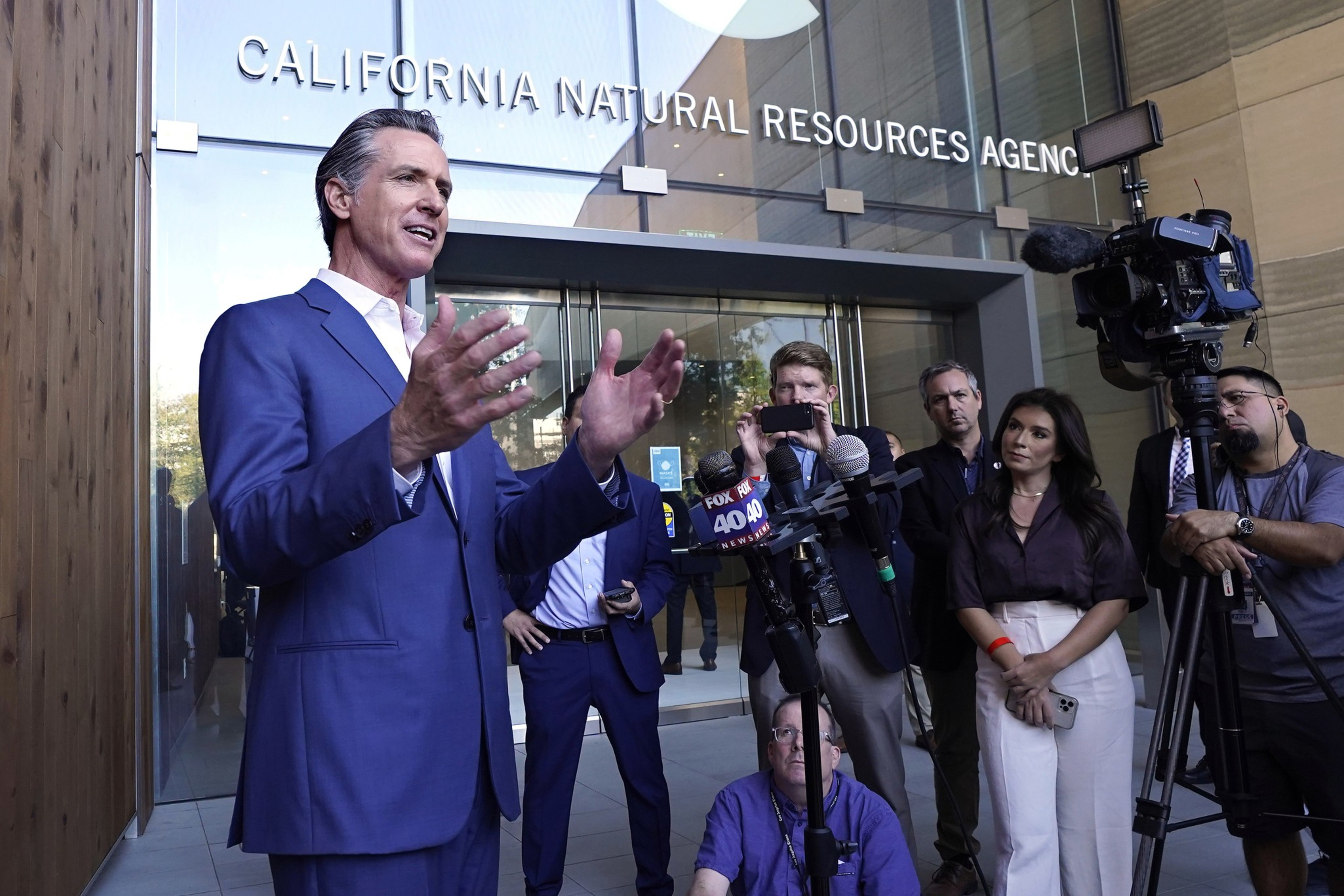 Gov. Gavin Newsom speaks in front of reporters outside of a building.