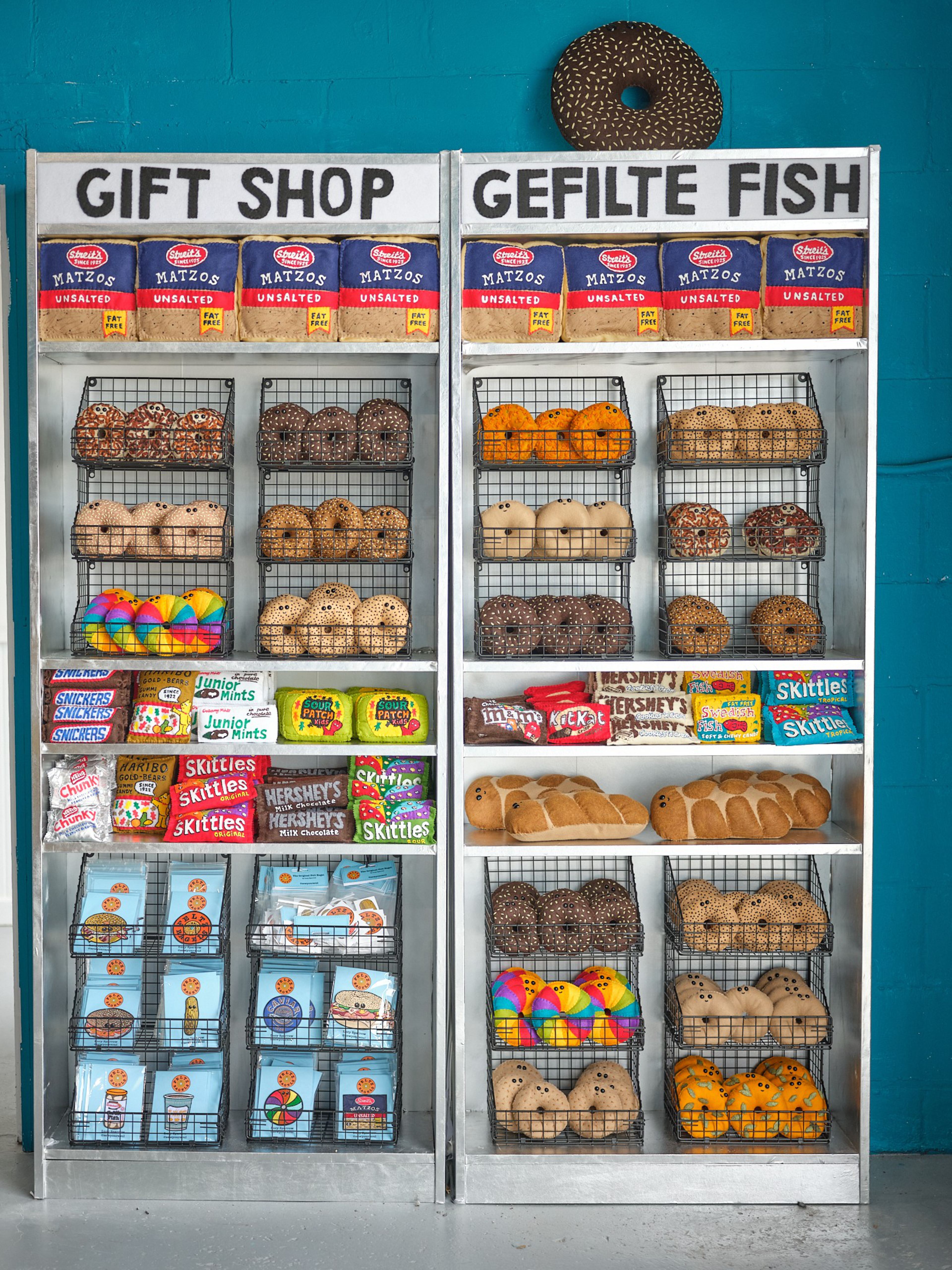 A stand holds rows of bagels and other food items made out of felt.