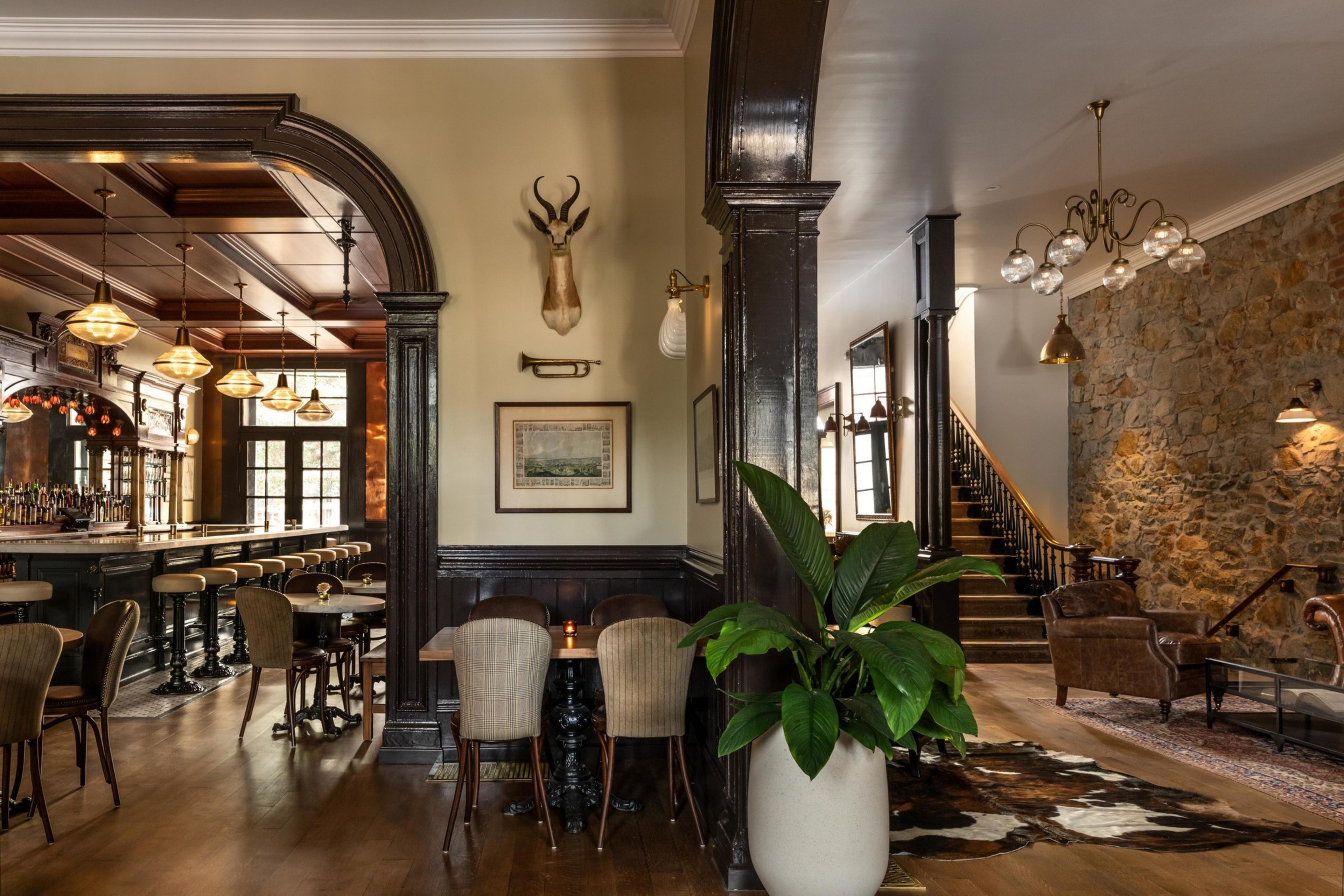 A large bar sits in the back of a dining area with a green indoor plant and taxidermy on the wall