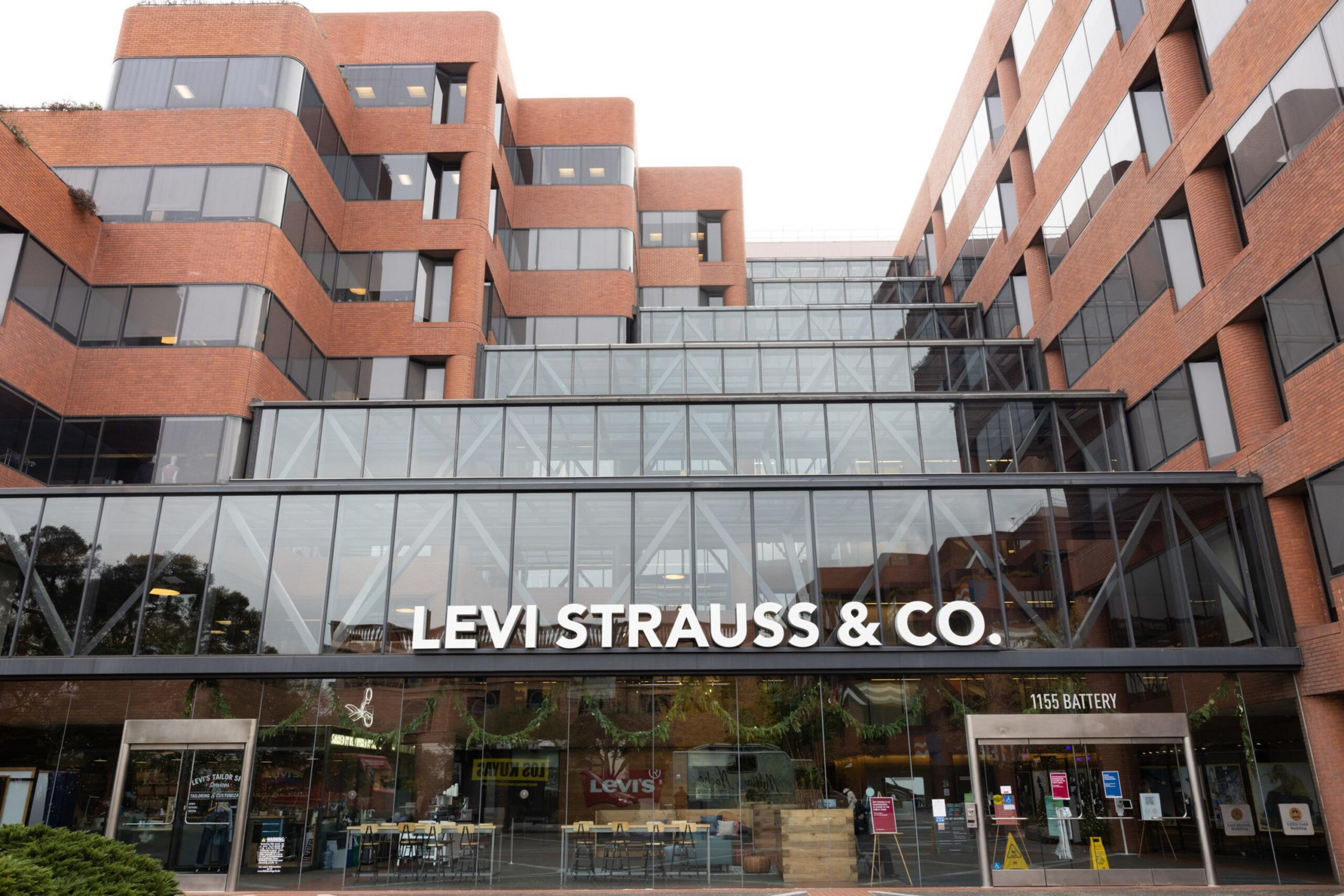 A modern brick office building with large glass windows displays the "Levi Strauss & Co." sign above the main entrance at 1155 Battery.