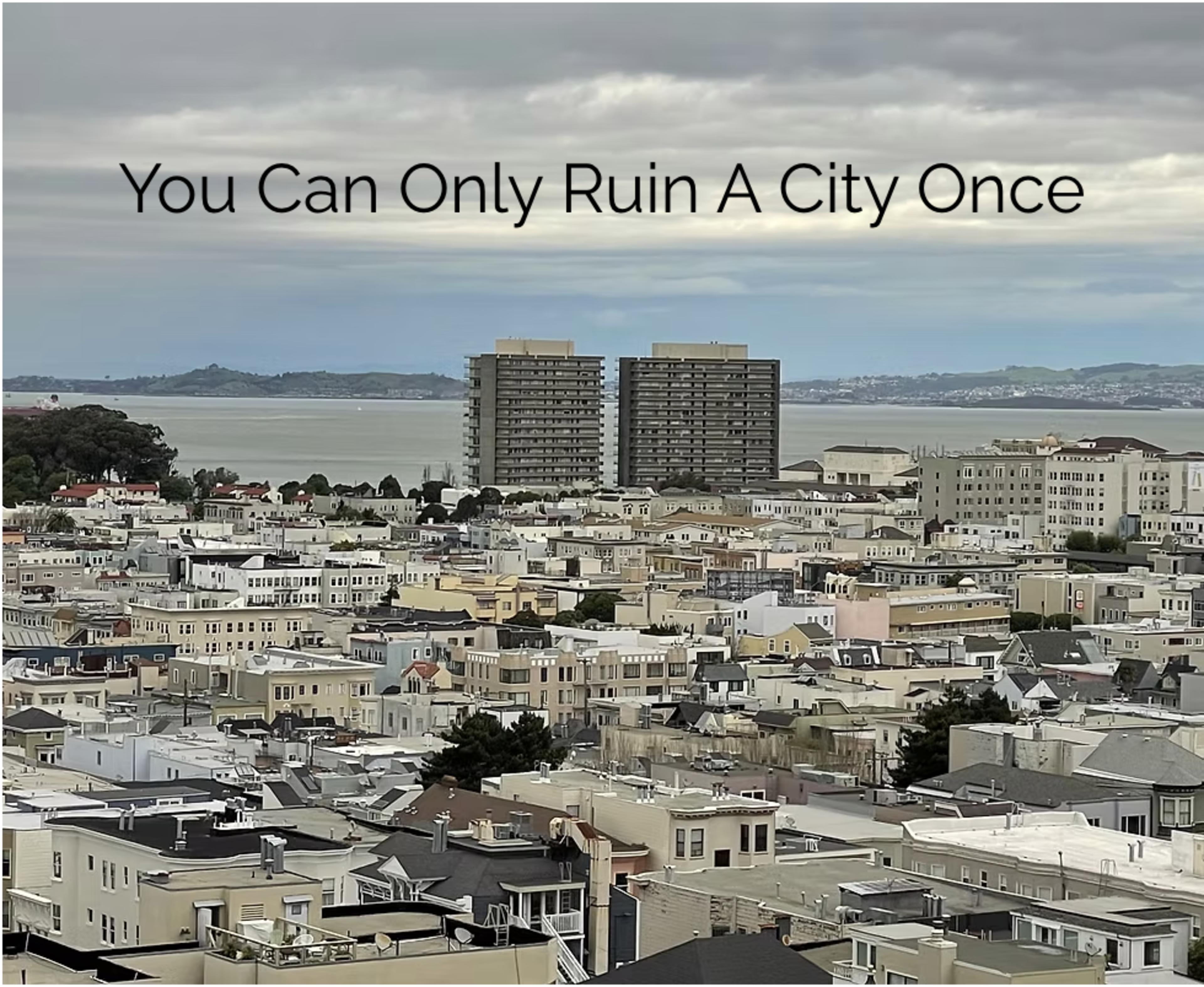 A cloudy cityscape with numerous low-rise buildings, two tall apartment towers near the water, and the text “You Can Only Ruin A City Once” above.
