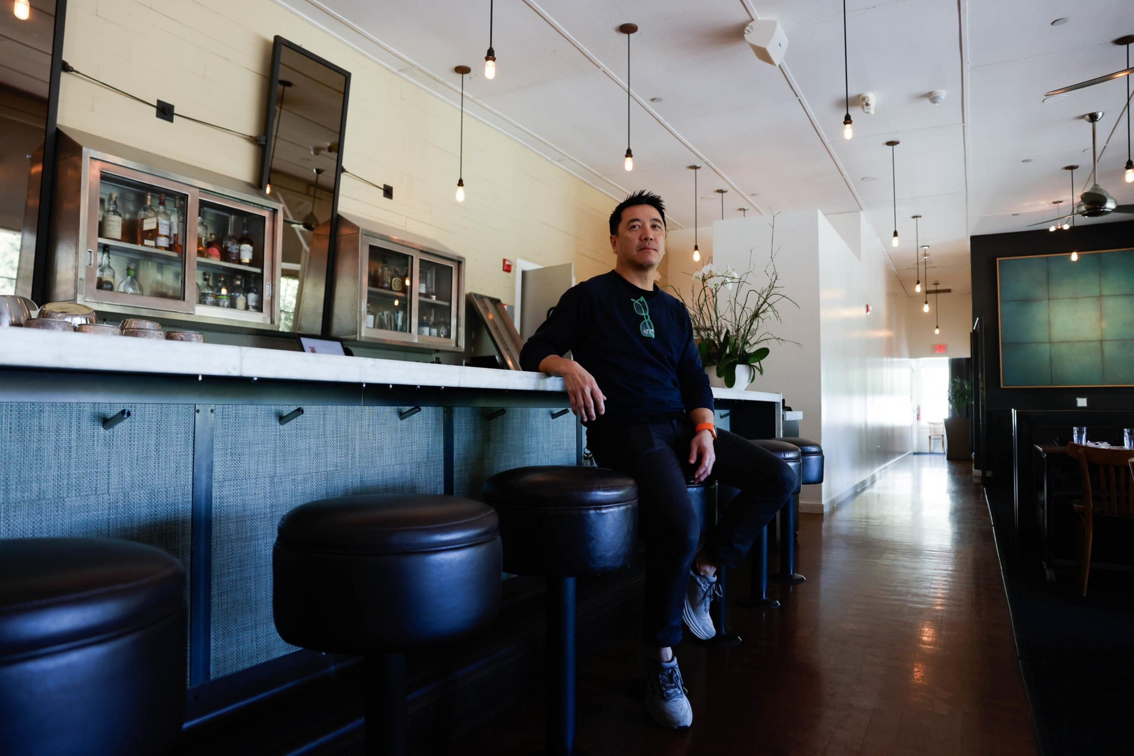 A man leans against a restaurant bar.