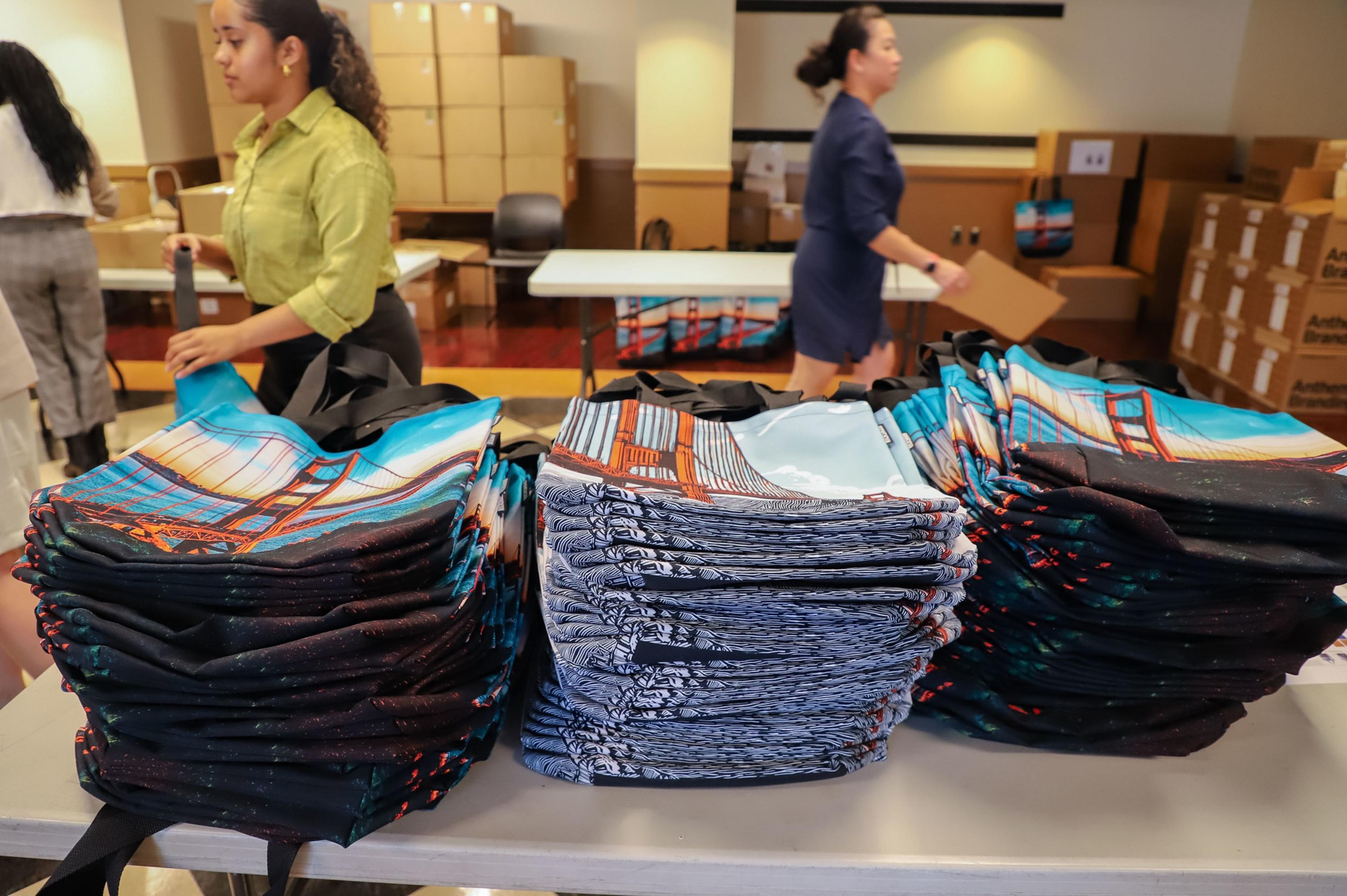A stack of tote bags with the Golden Gate Bridge on them stands on a table.