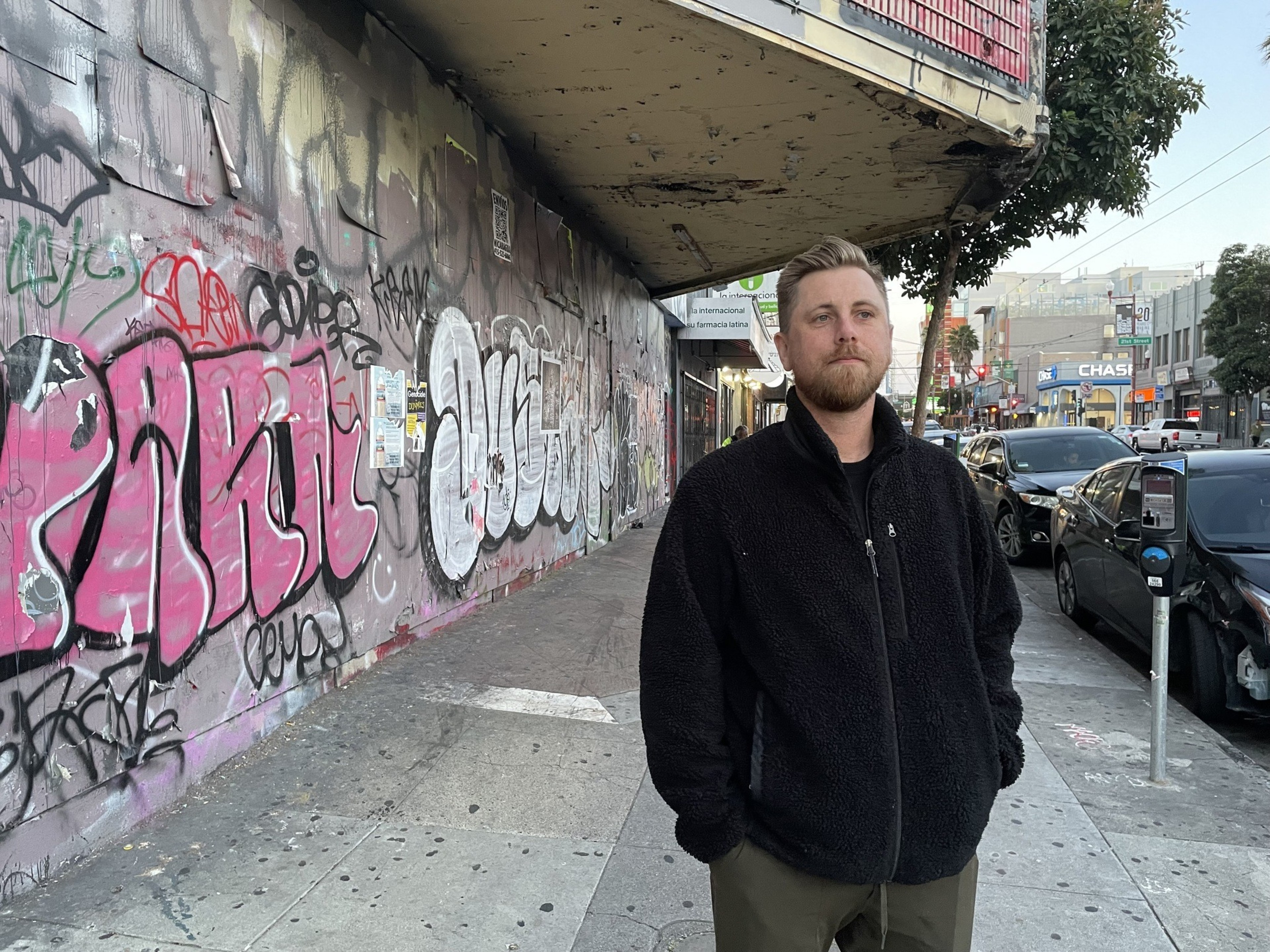 A man stands in front of a ruined movie theater.