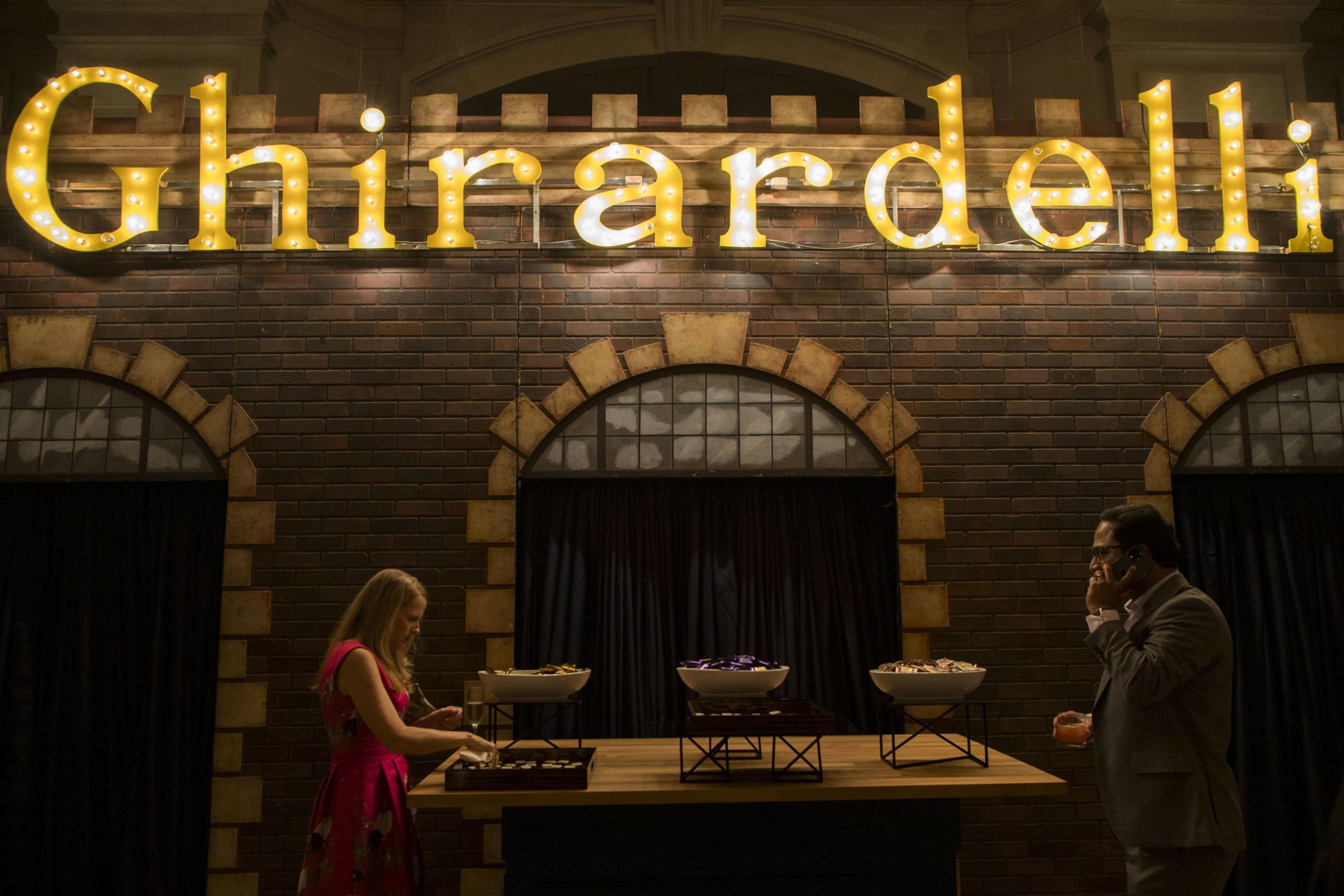 Two people grabbing food under lights at a welcoming party at city hall.