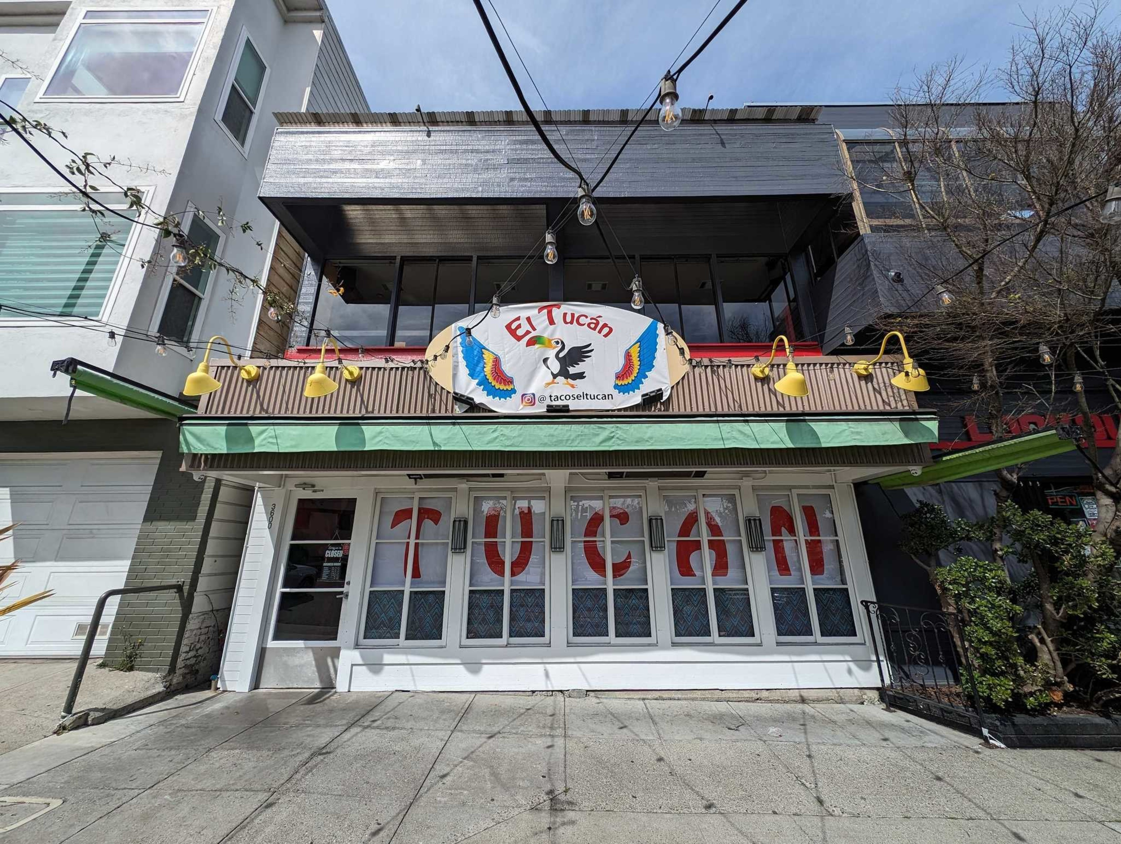Mexican restaurant "El TucÃ¡n" with a colorful sign, chili pepper decor, and a green awning under a sunny sky.
