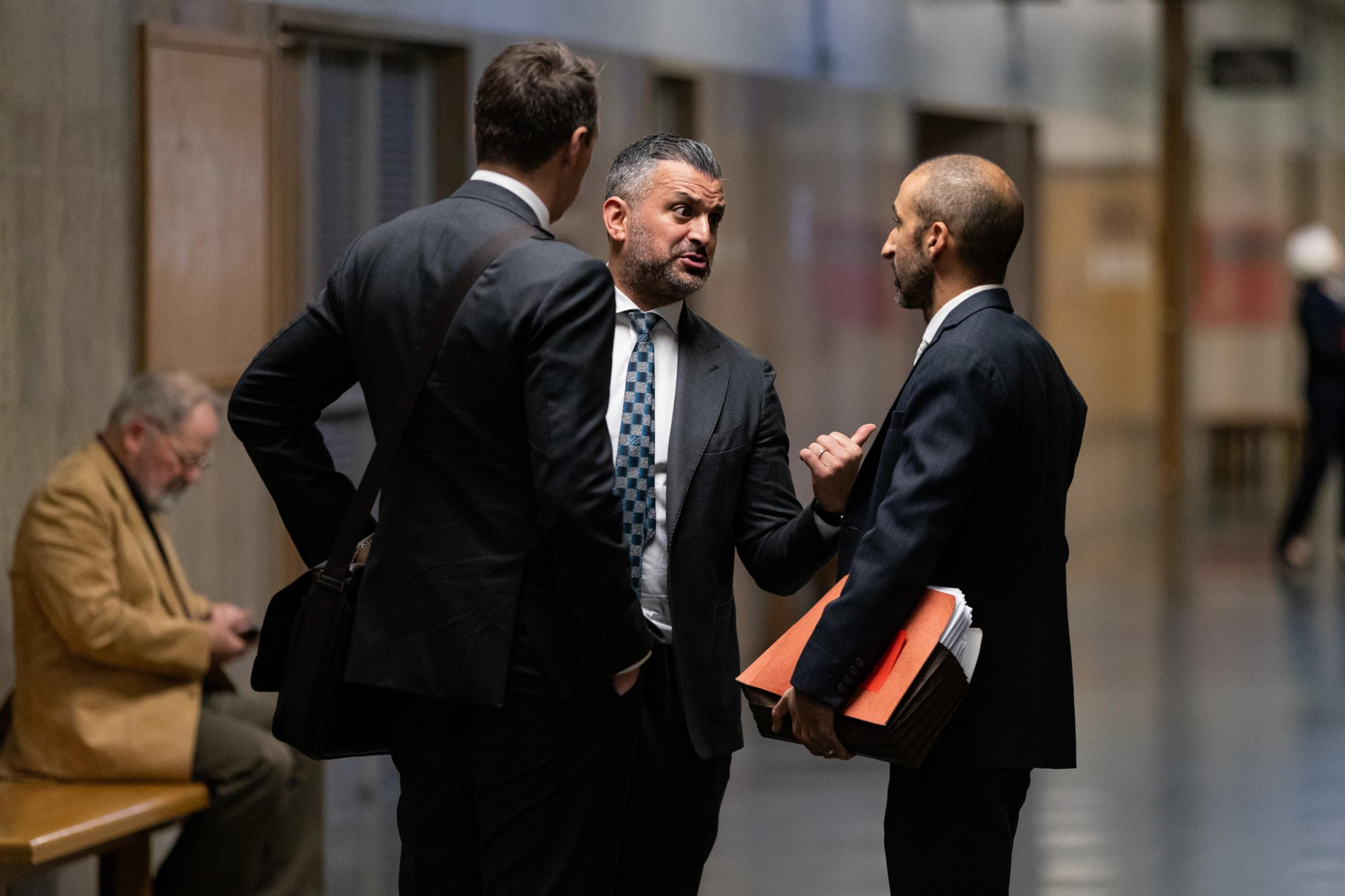 Three men stand in a hallway