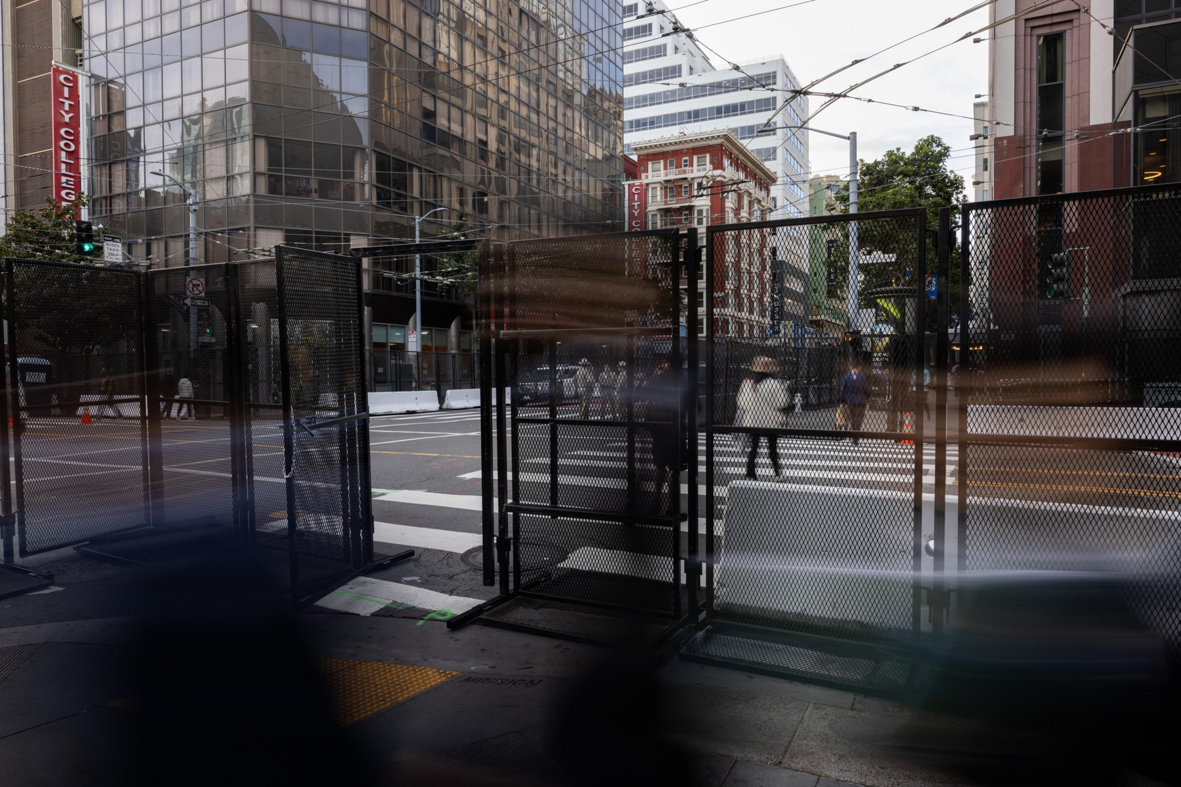 A large black fence on a city street corner.