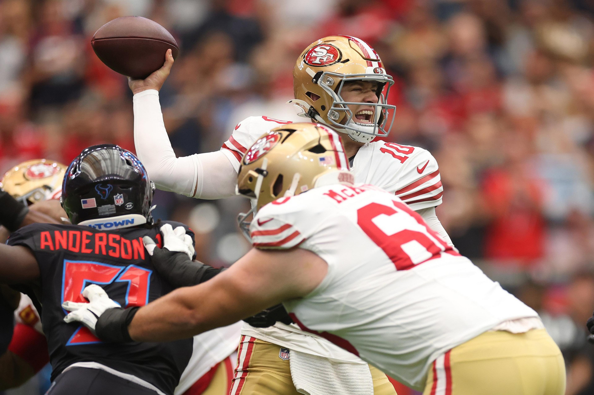 A San Francisco 49ers quarterback prepares to throw a pass while his offensive lineman blocks a Houston Texans defender.