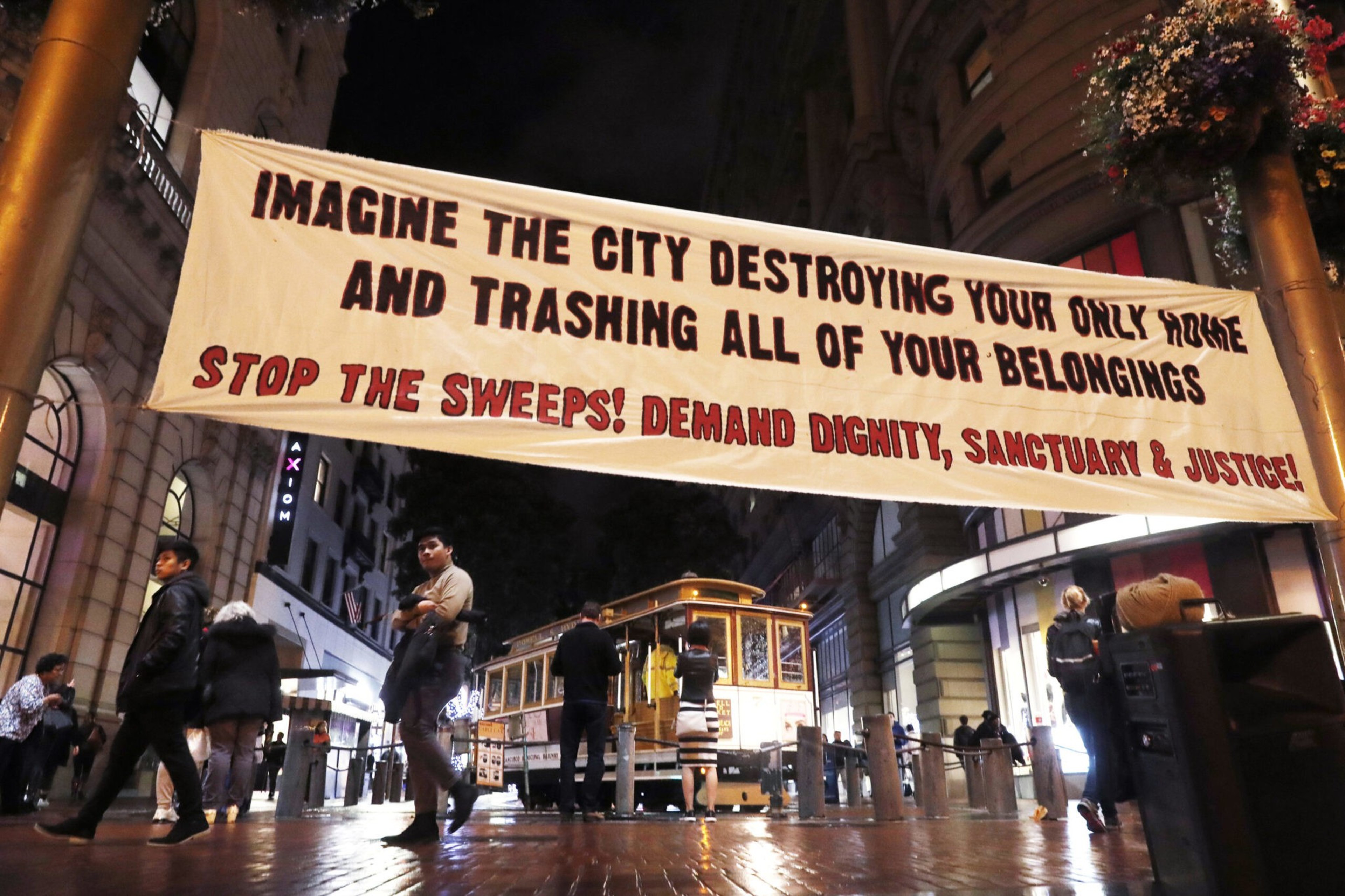 A large banner reads, "Imagine the city destroying your only home and trashing all your belongings. Stop the sweeps! Demand dignity, sanctuary & justice!"
