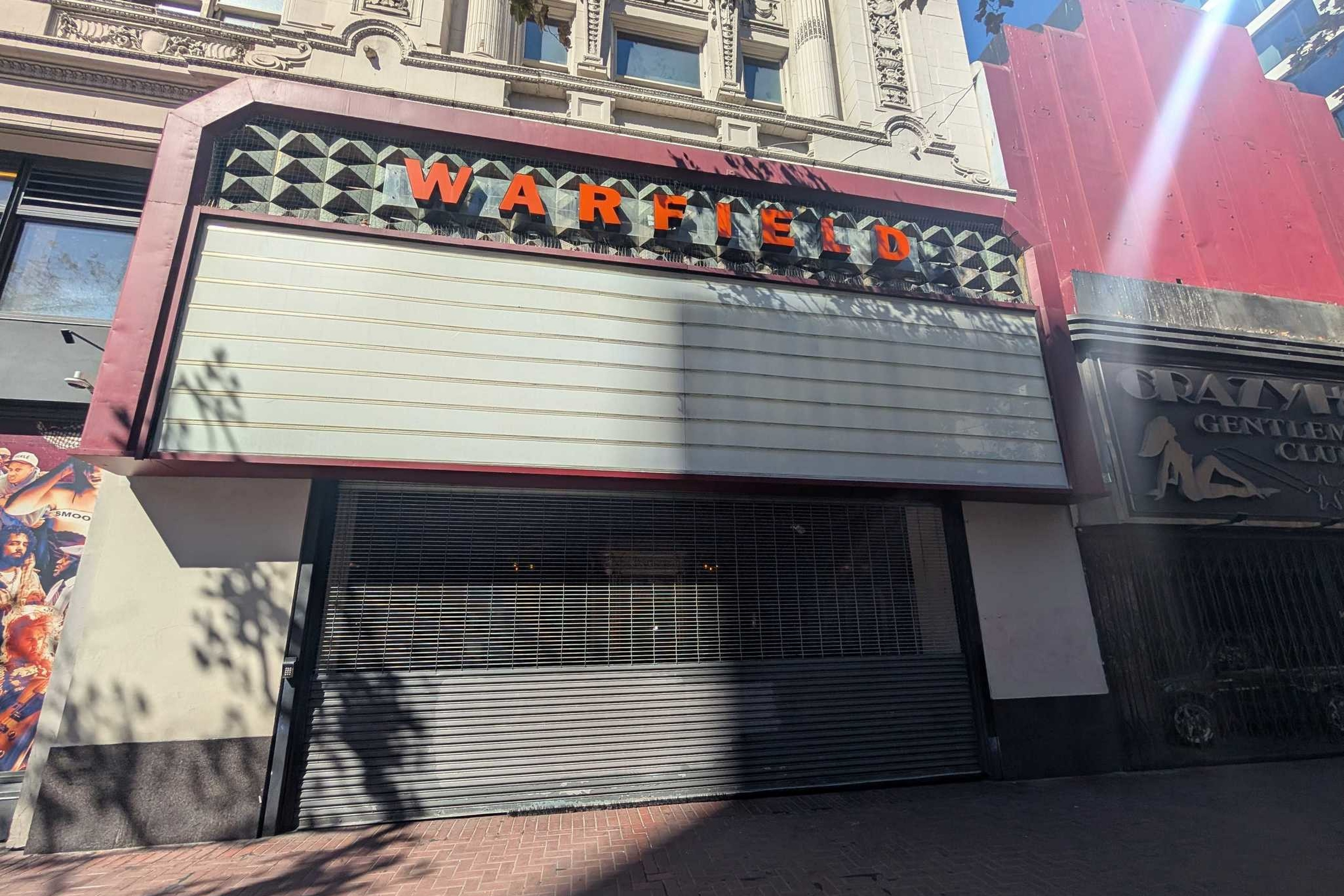 A closed storefront with a blank marquee sign above showing the word "WARFIELD" in orange letters on a decorative facade.