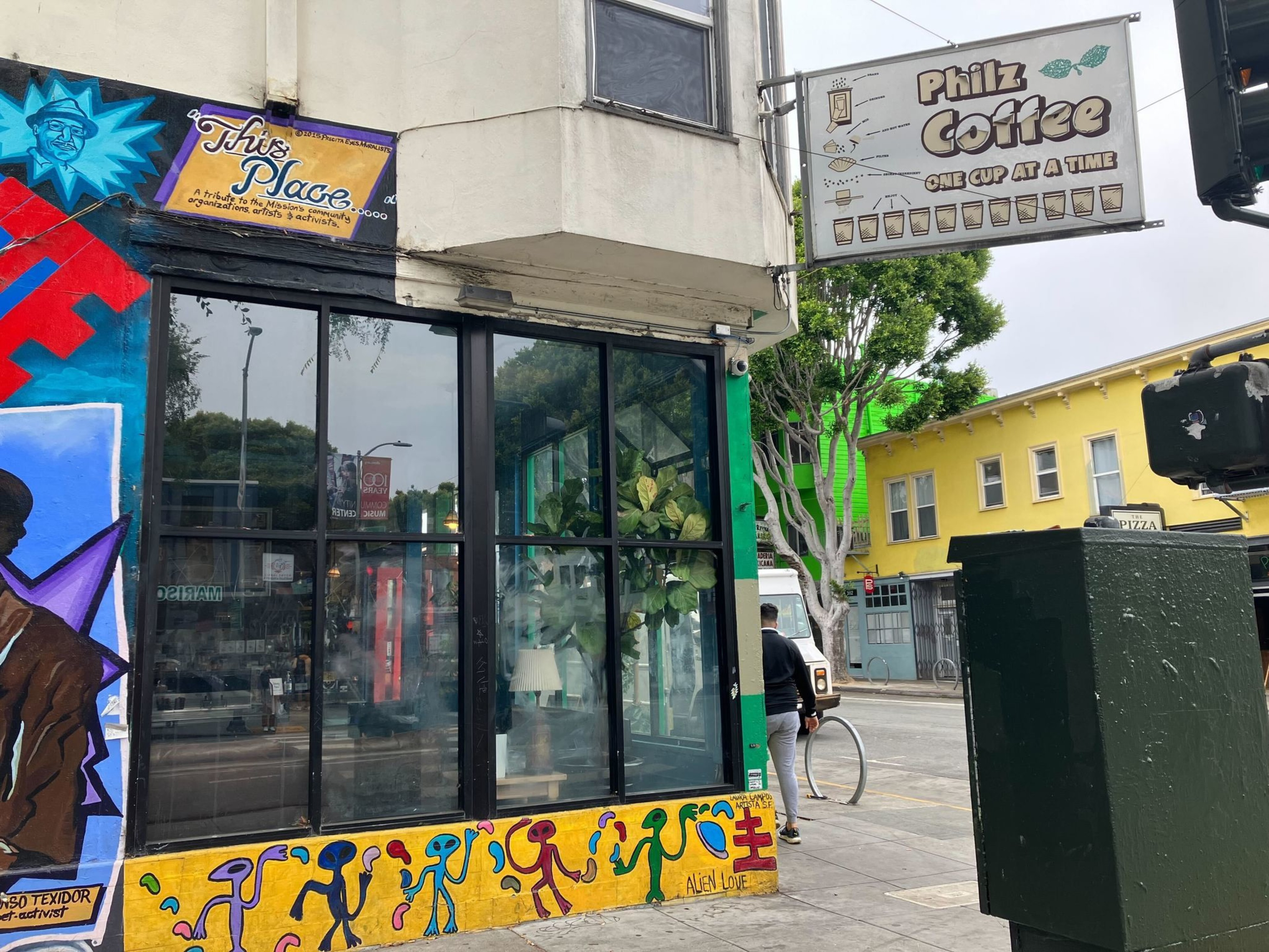 Person walks by corner glass storefront with yellow mural design