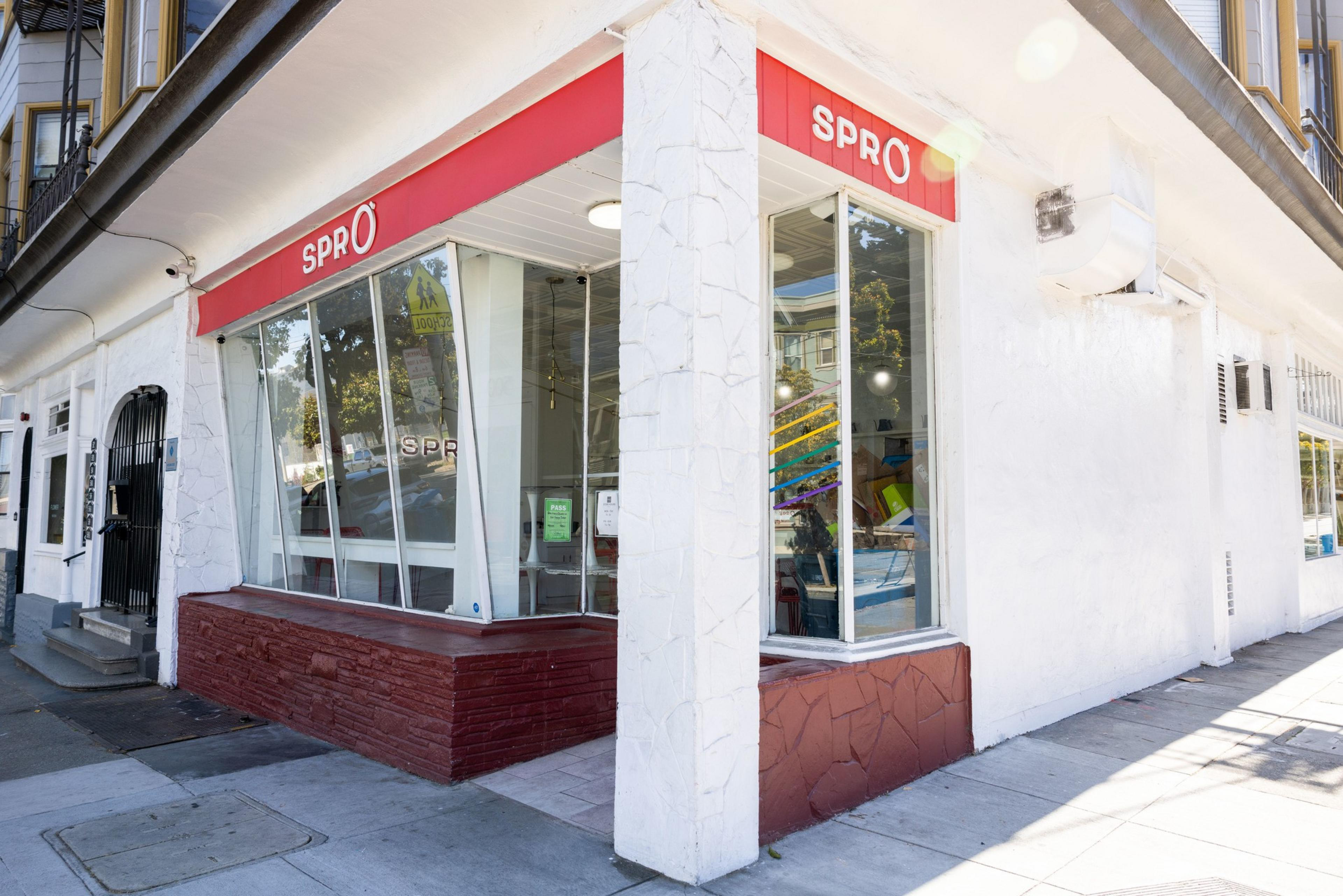 A white-painted building's corner shows the entrance to a cafe under red-painted signage.