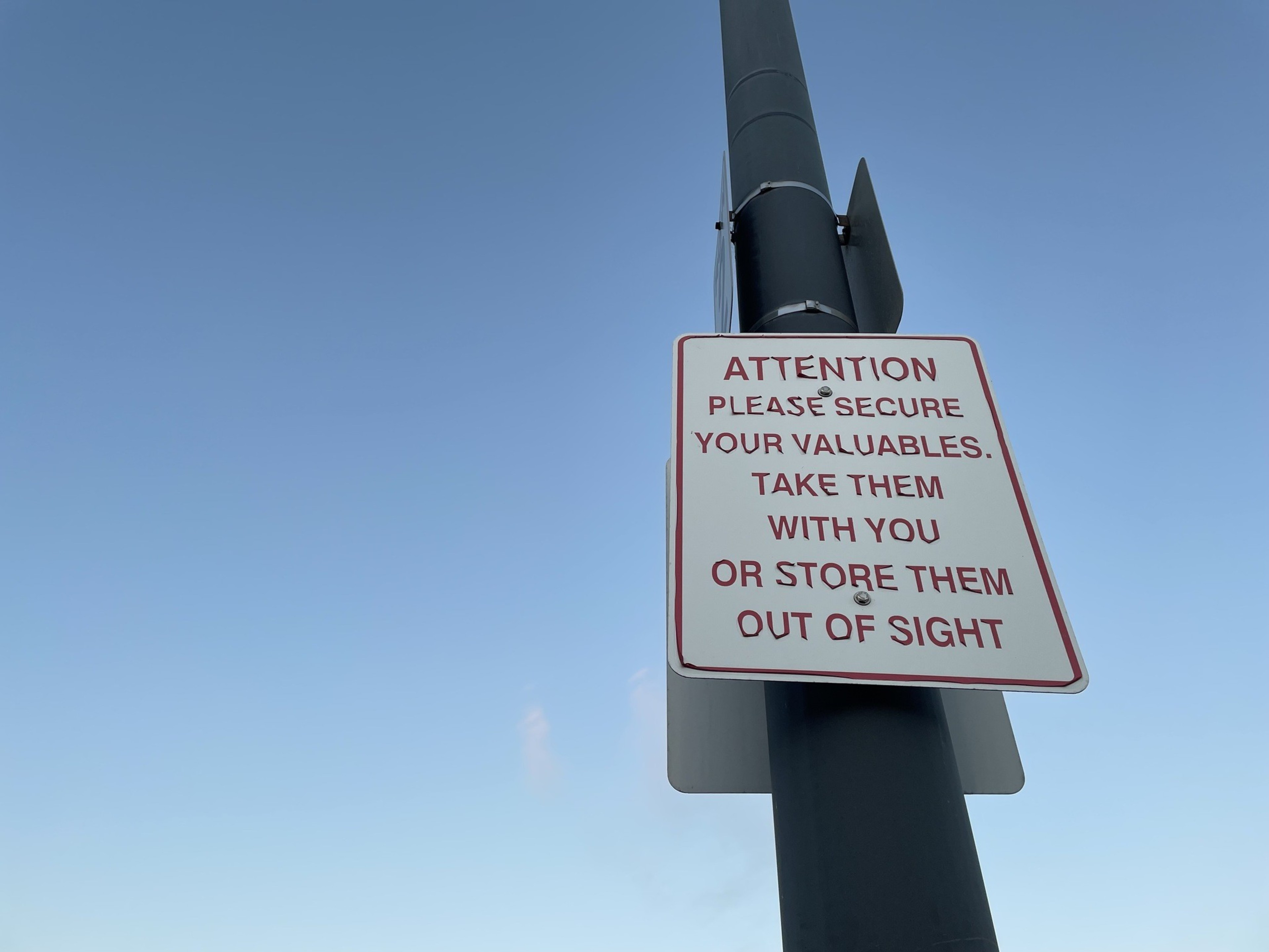 A sign in a parking lot of a commercial plaza near Oakland International Airport warns drivers not to leave belongings in their car.