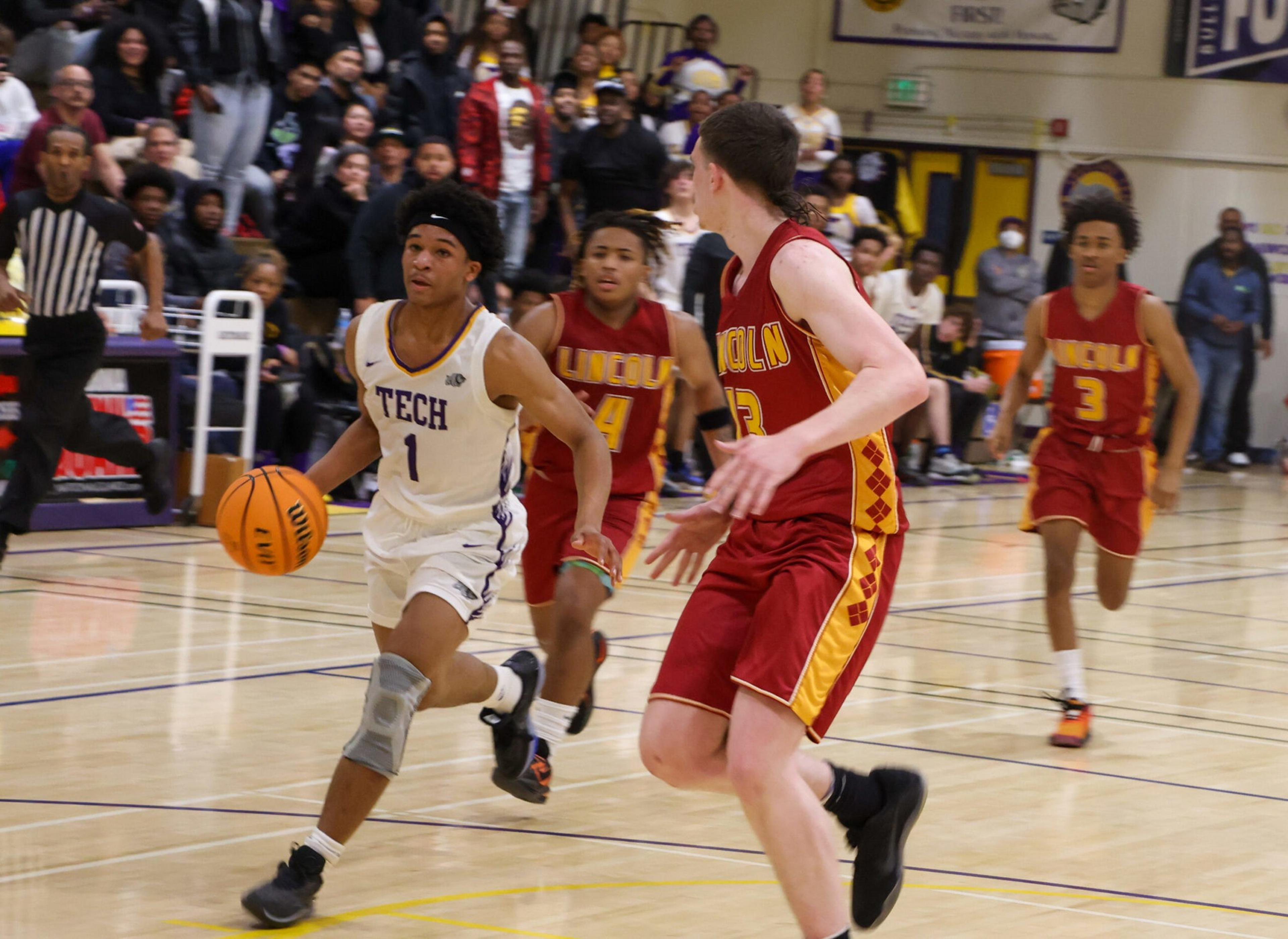 A basketball player in a white "Tech" uniform dribbles the ball while three defenders in red and yellow "Lincoln" uniforms approach.