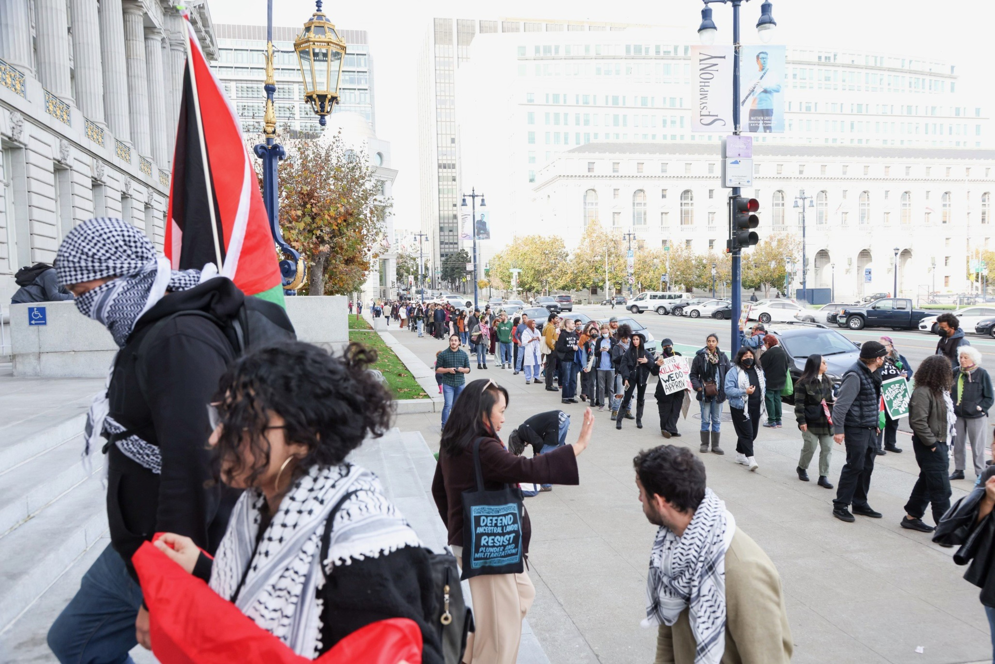 A long line of people are outside City Hall for the public comment portion of a board of supervisors meeting later where Supervisor Dean Preston will introduce a resolution calling for a ceasefire in the Israel-Hamas war.