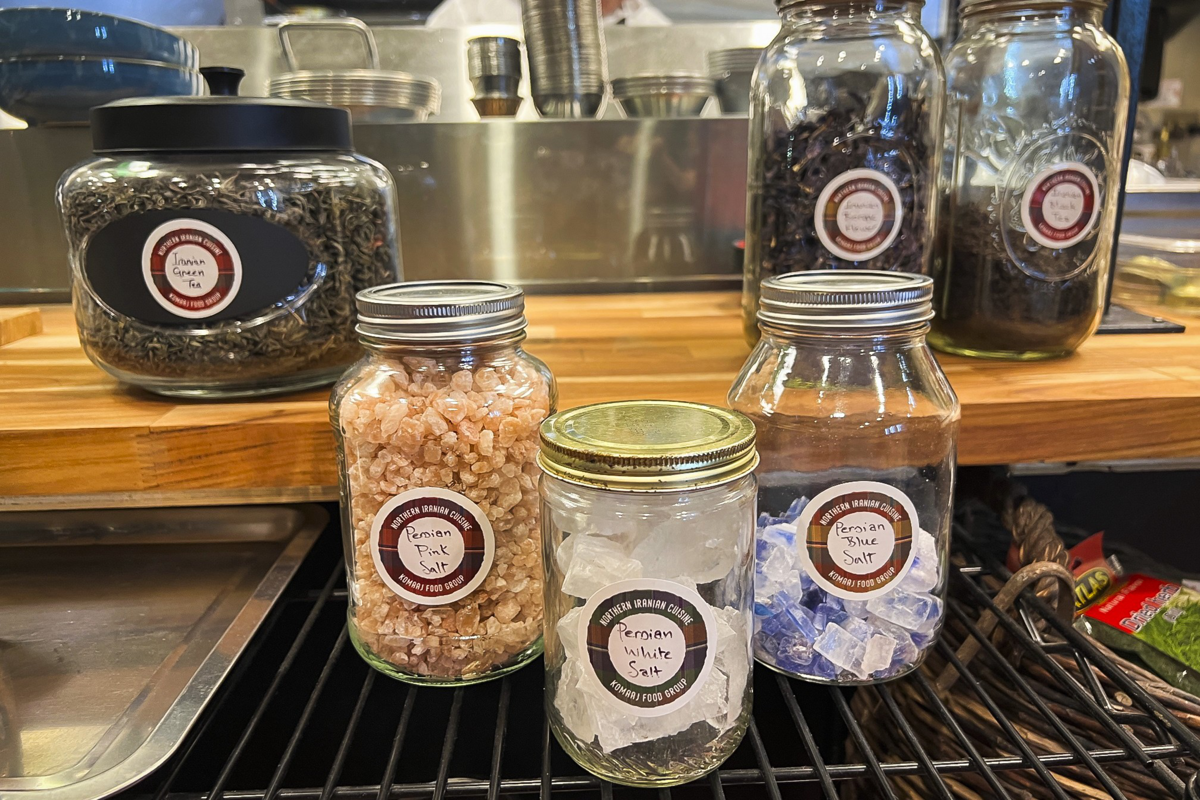 Four jars with various salts on a shelf; labels read &quot;Persian Pink&quot;, &quot;White&quot;, and &quot;Blue&quot; salt.