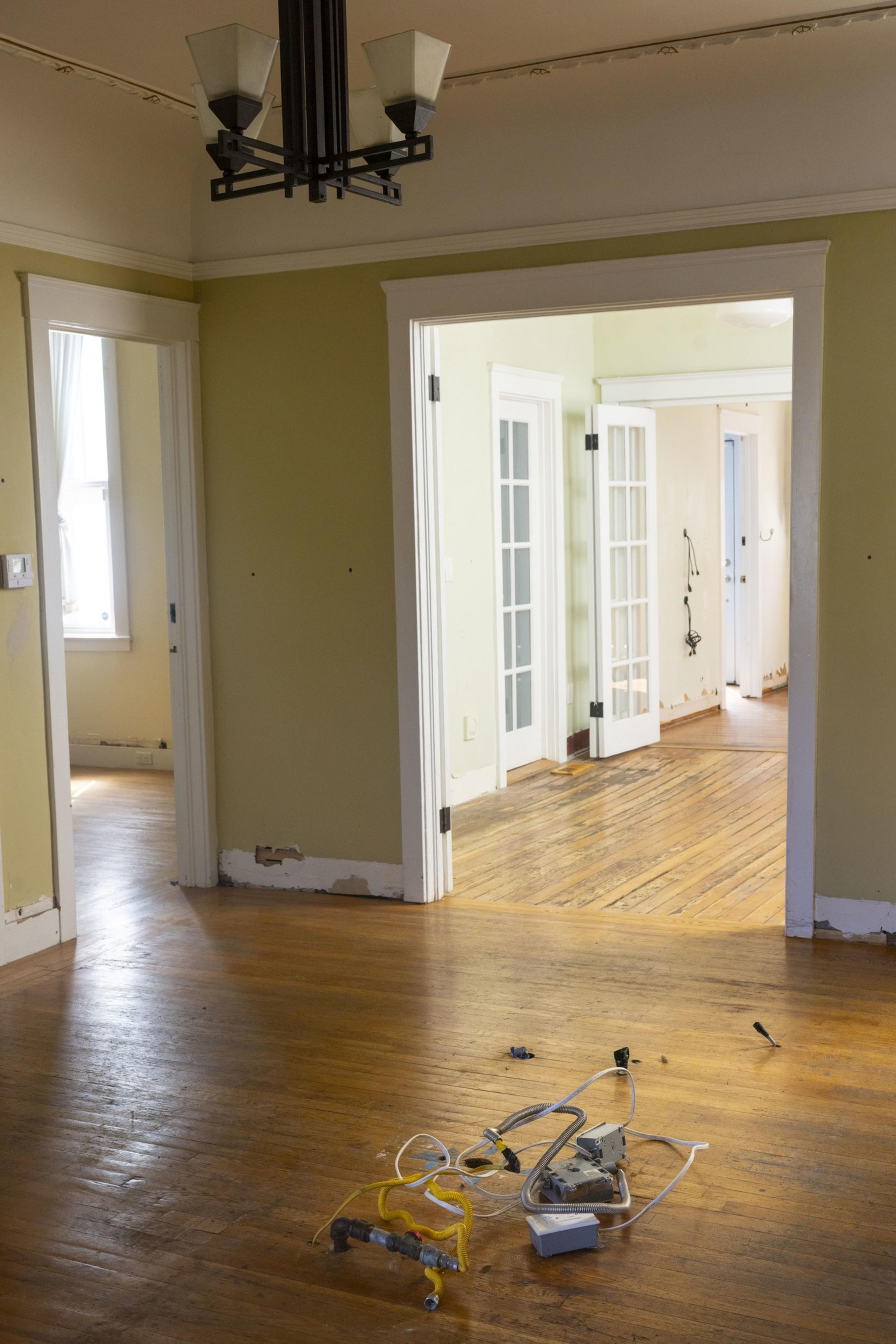 Peeled paint and flood-damaged floorboards in a sunlight home.