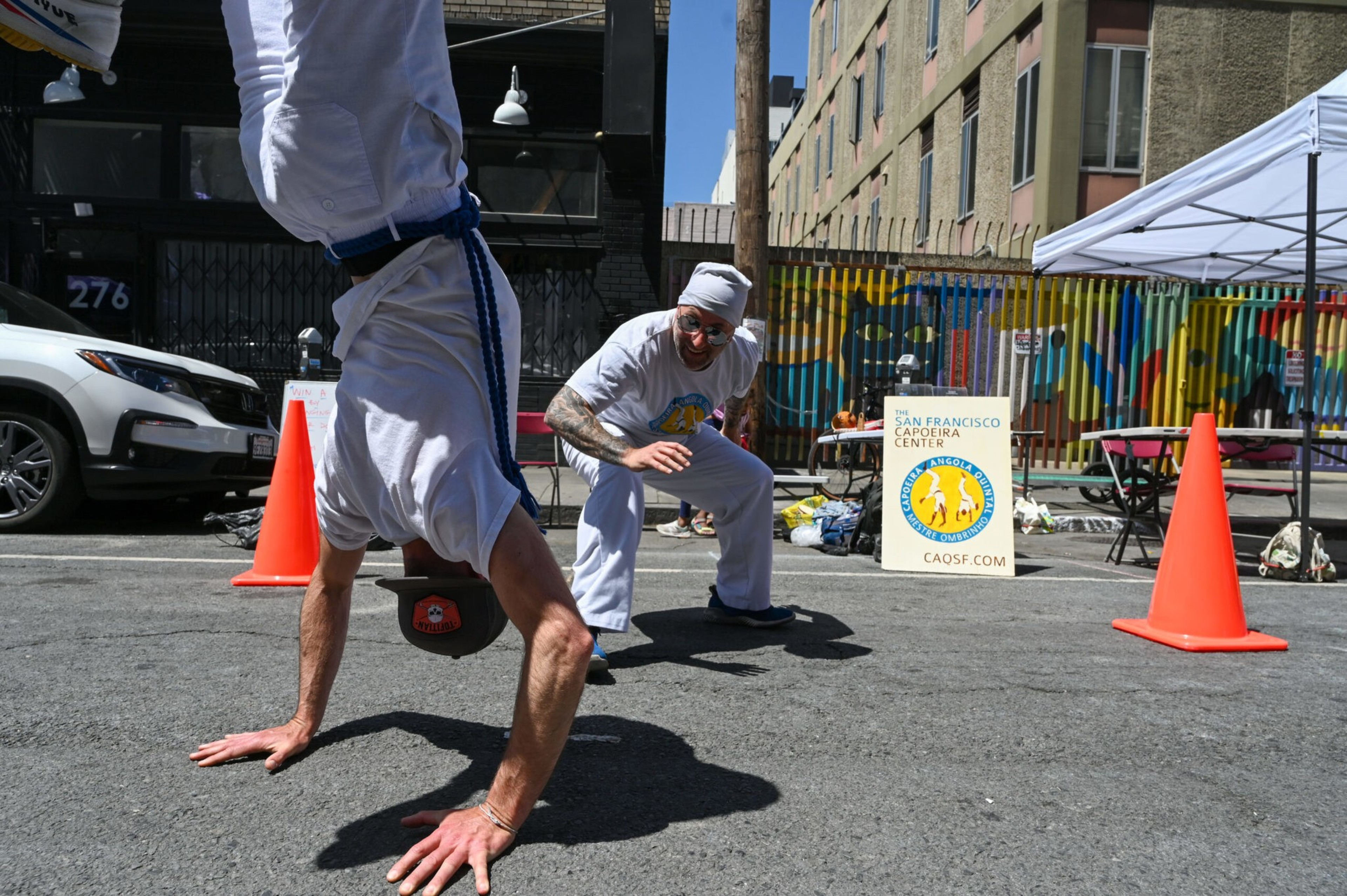 A person in white is doing a handstand while someone else watches.