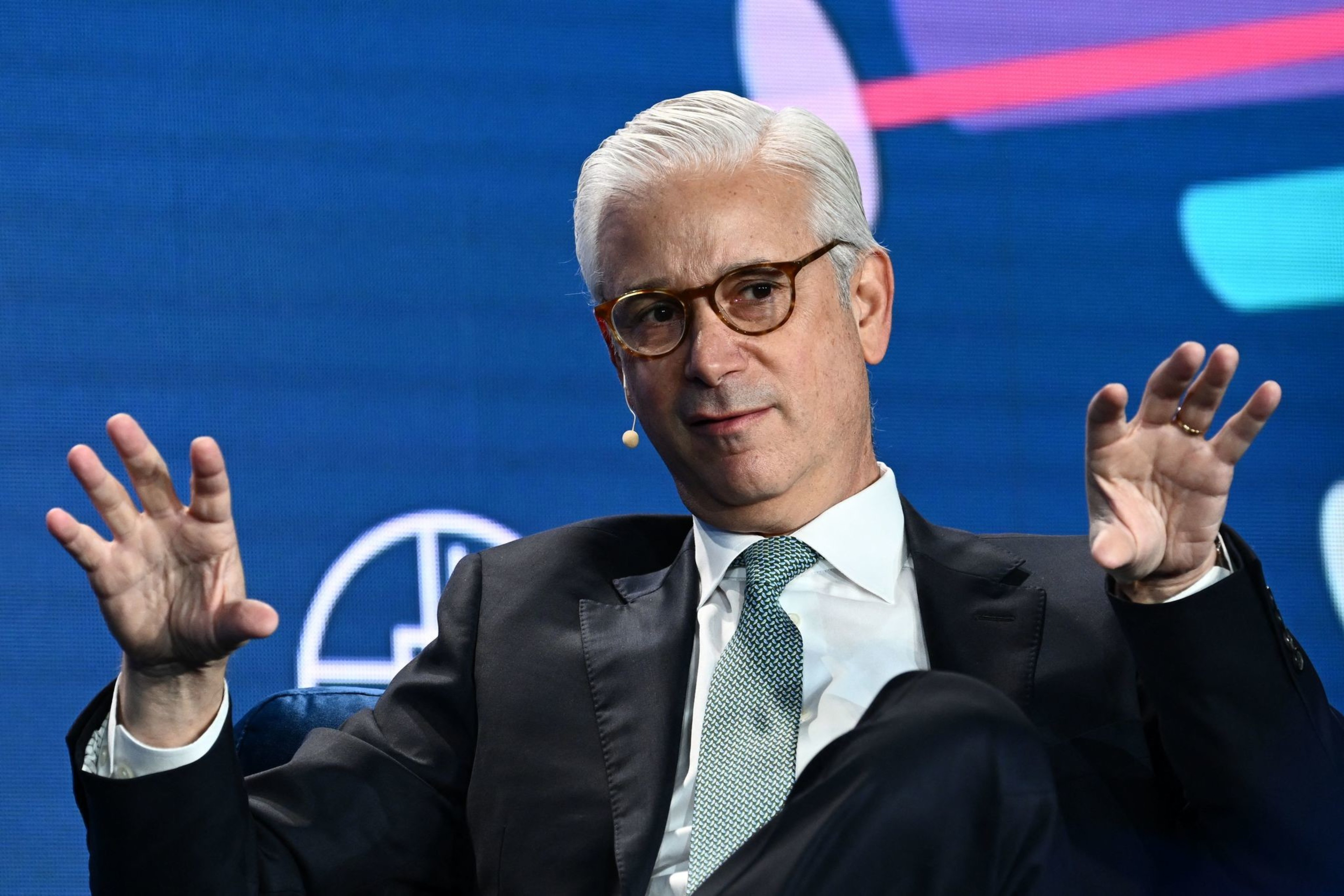 Man in a suit sitting with his hands out