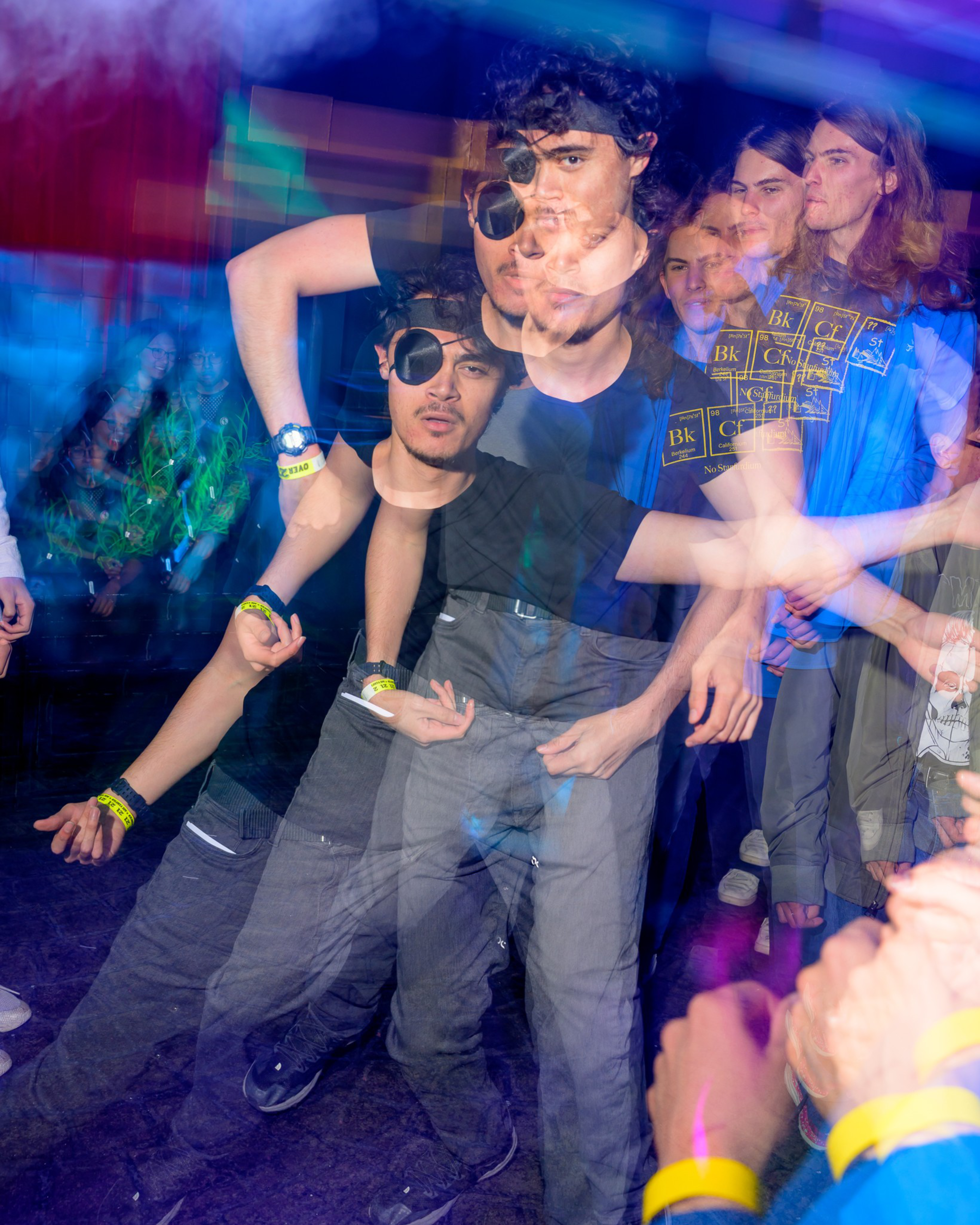 A vibrant, blurred image shows people dancing energetically under colorful lights. One person is highlighted with repeated ghost-like movements, adding to the lively atmosphere.