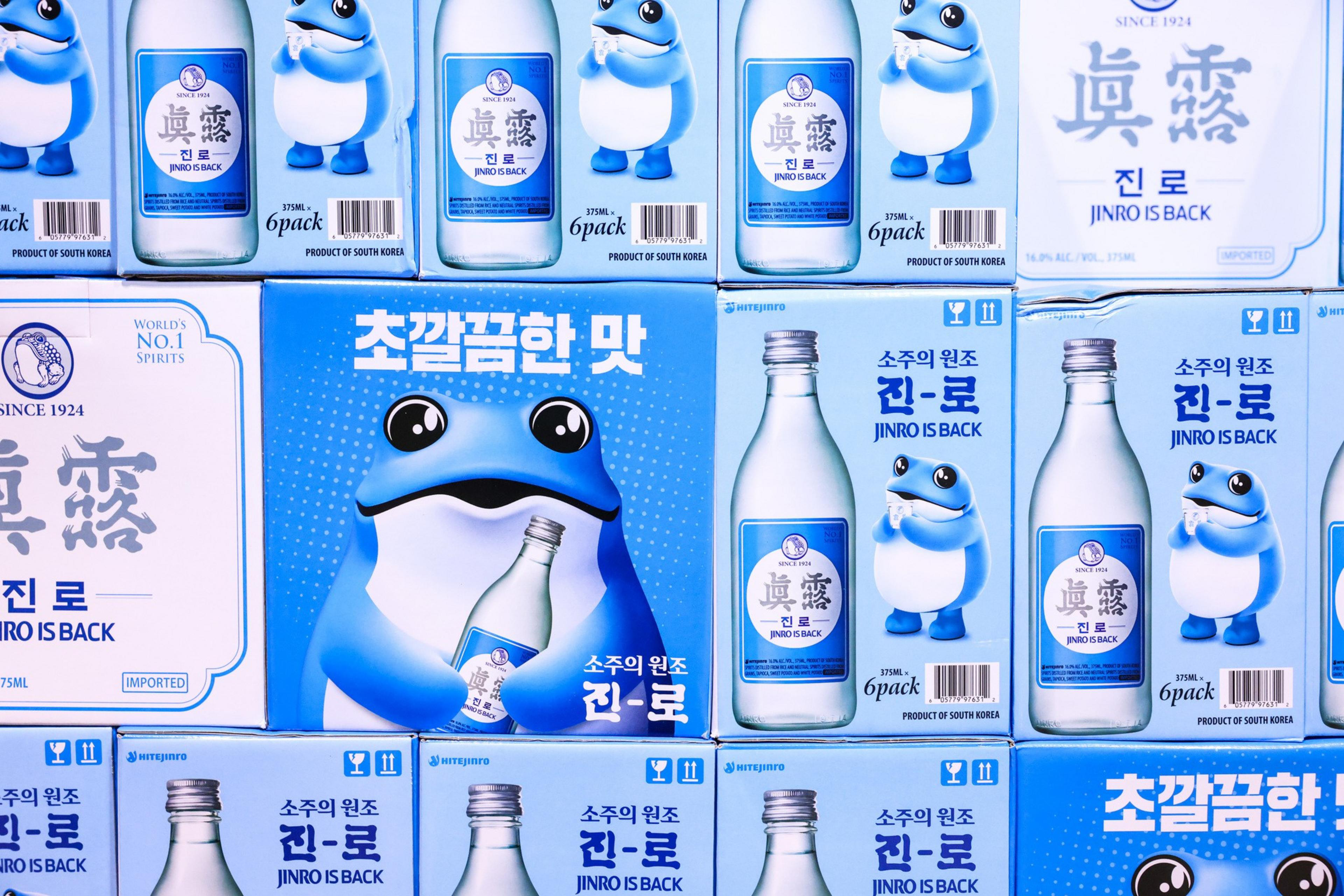 The image shows boxes of Jinro soju featuring a blue frog mascot, bottles, and various Korean and English text promoting the product as &quot;Jinro is Back.&quot;