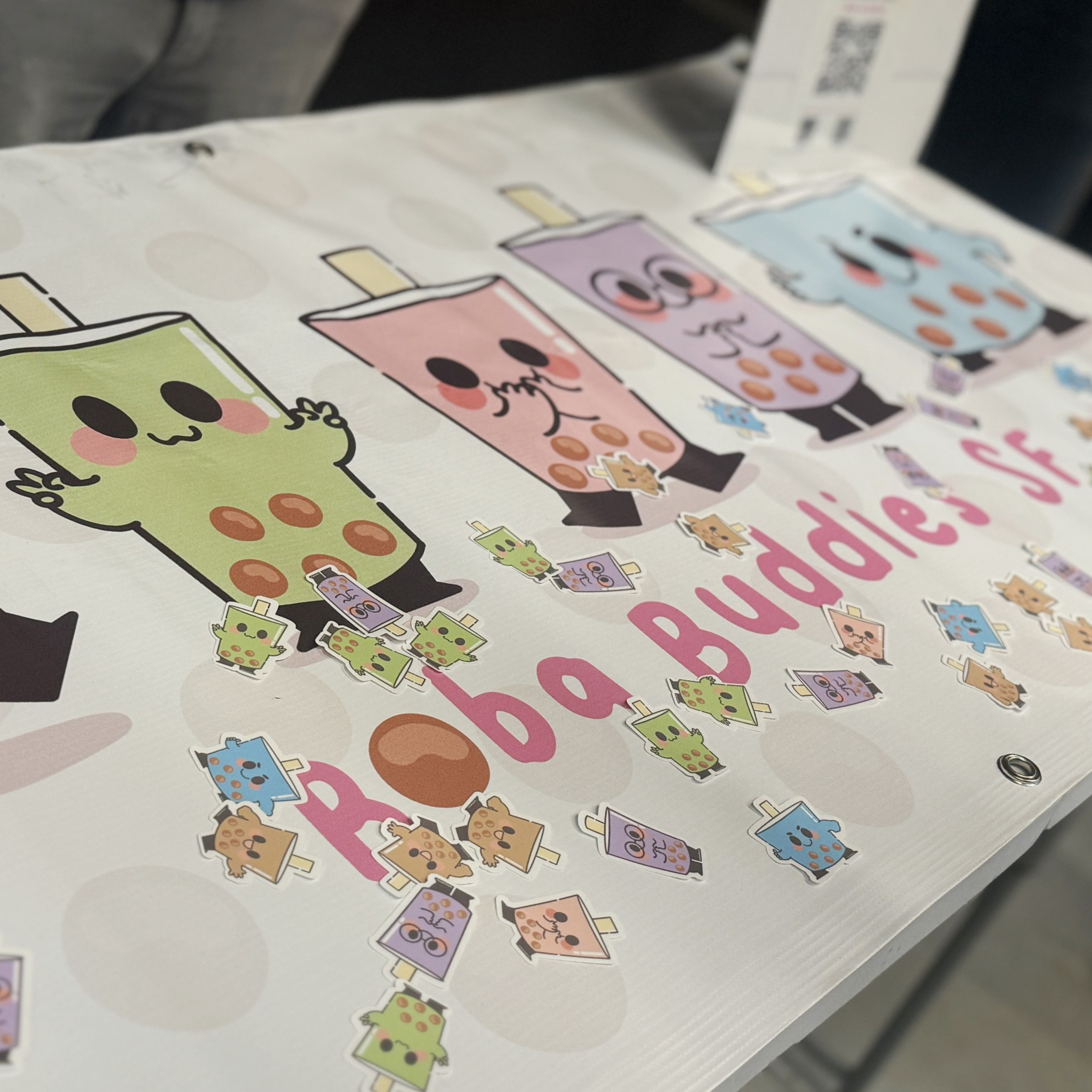 The image shows a banner with cute cartoon bubble tea characters in various colors with faces, arms, and legs, labeled &quot;Boba Buddies SF&quot; surrounded by small stickers of the characters.