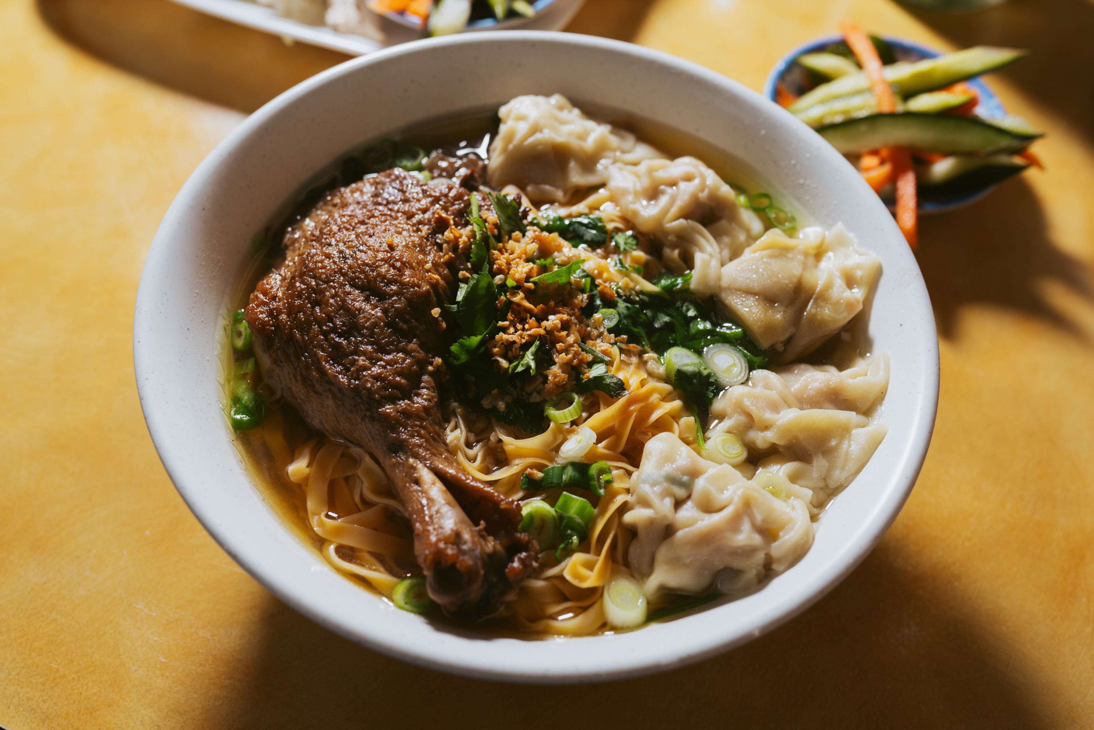 a bowl of noodle soup with a braised duck leg, shot from above
