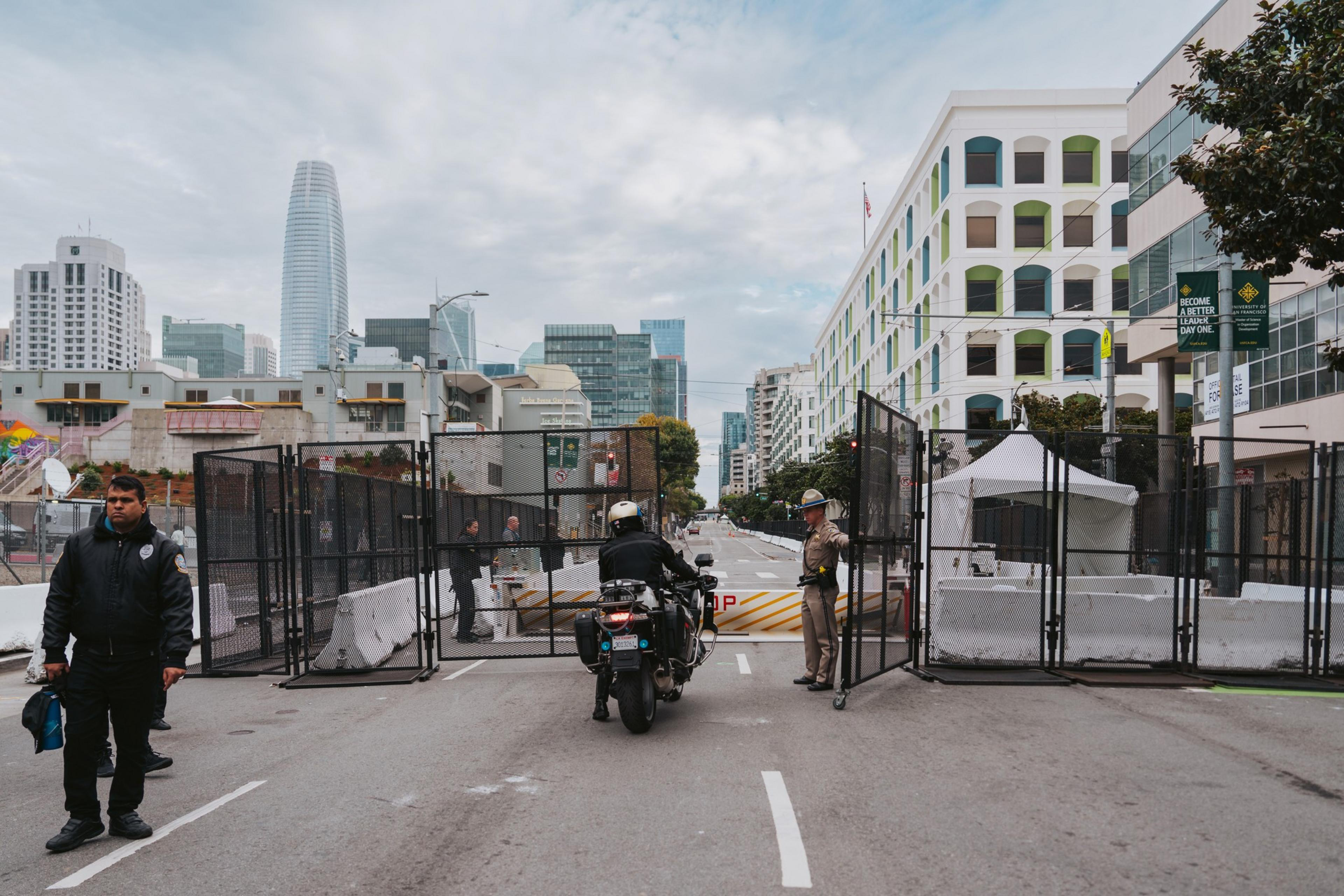 A California Highway Patrol (CHP) officer lets a motorcycle officer through a large gate on a blocked street.