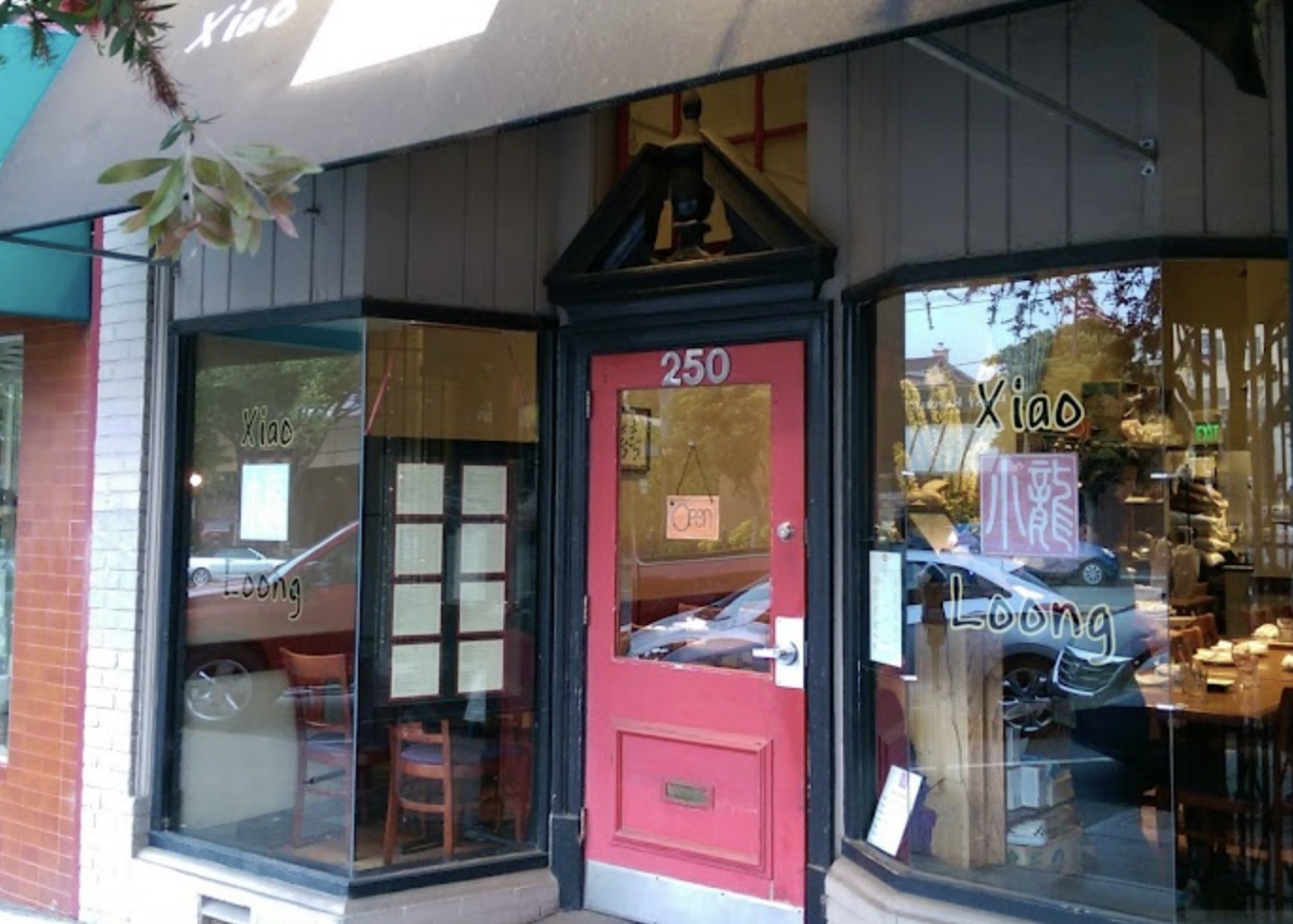 Street view of a restaurant with a black entrance and pink door.