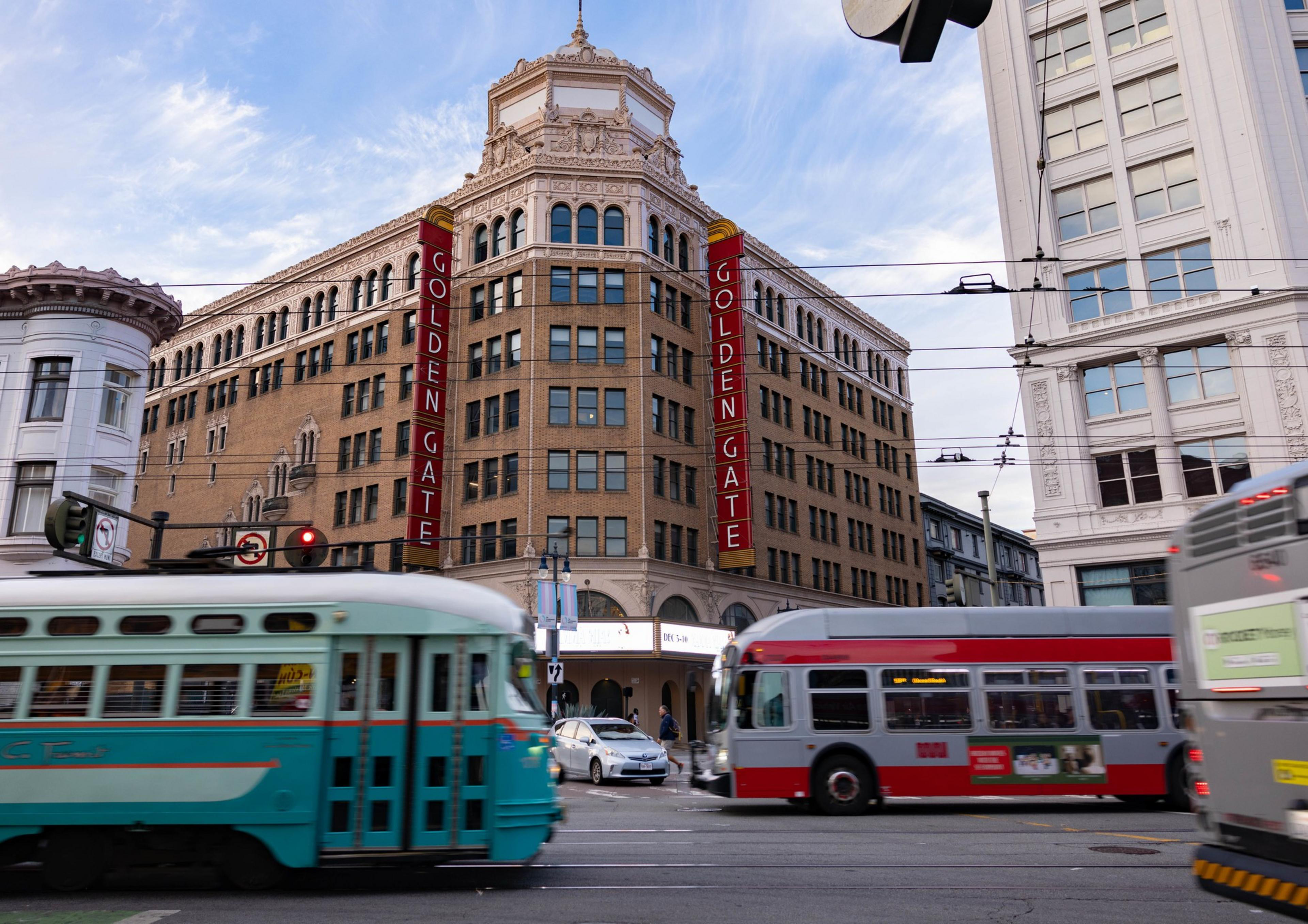 San Francisco Muni buses and streetcars on Market St. in San Francisco with the Golden Gate Theatre in the background.